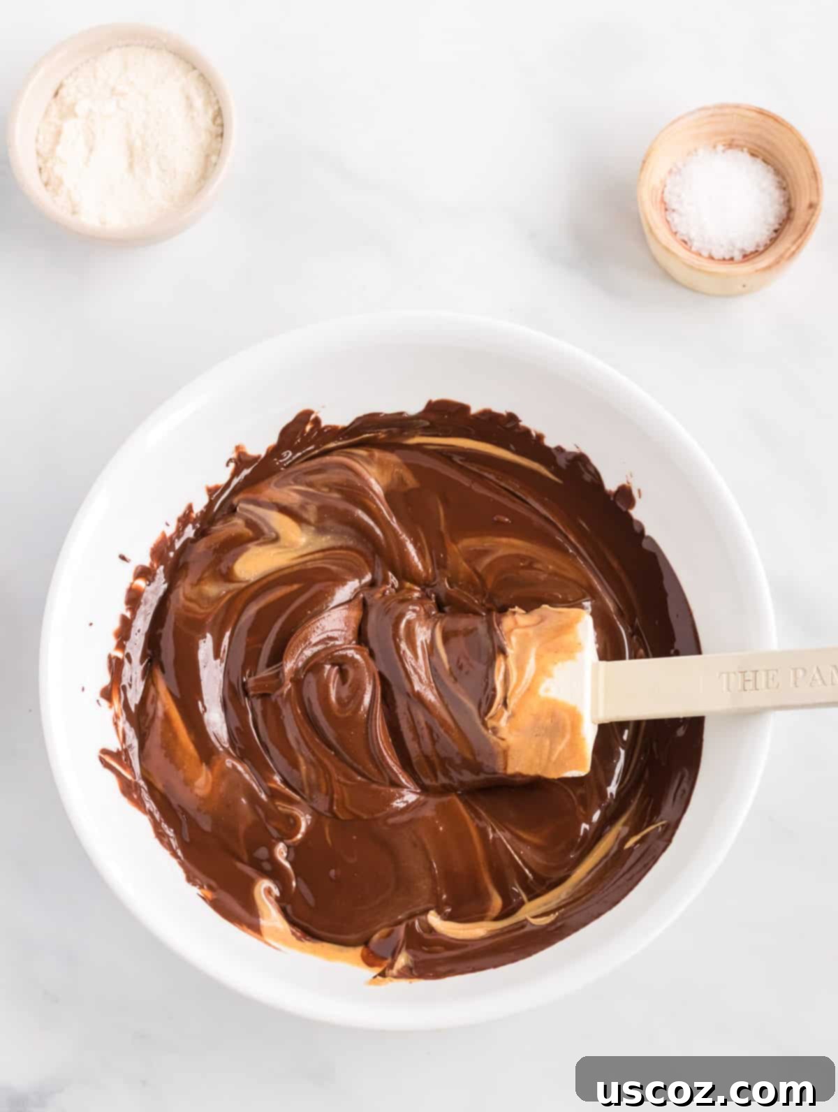 Decadent Vegan Chocolate Peanut Butter Fudge 4 A bowl showing melted chocolate and creamy peanut butter being stirred together, forming the base of the vegan fudge.
