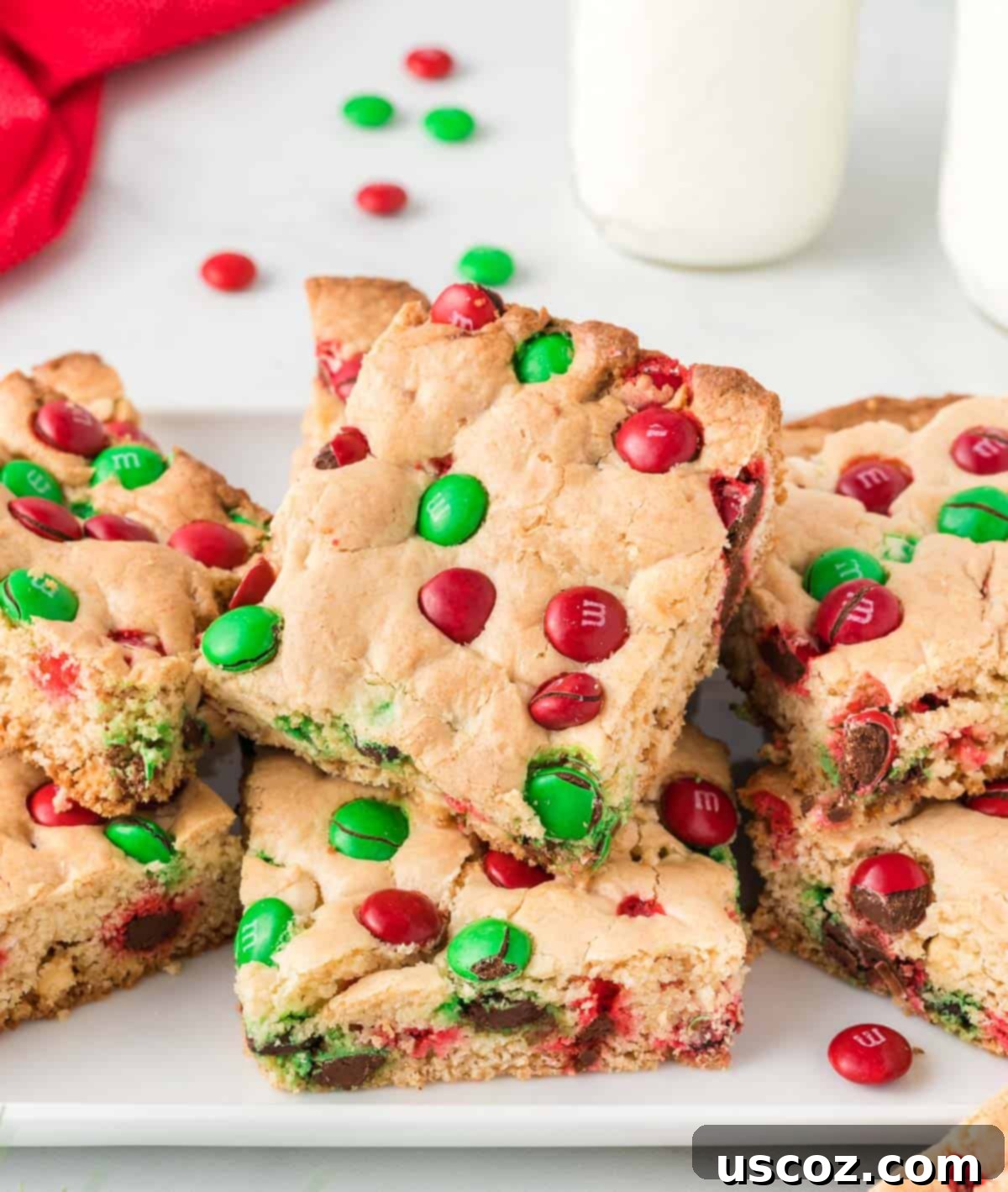 Merry Cookie Bar Magic 2 christmas cookie bars on a plate, featuring red and green M&M's and white chocolate chips