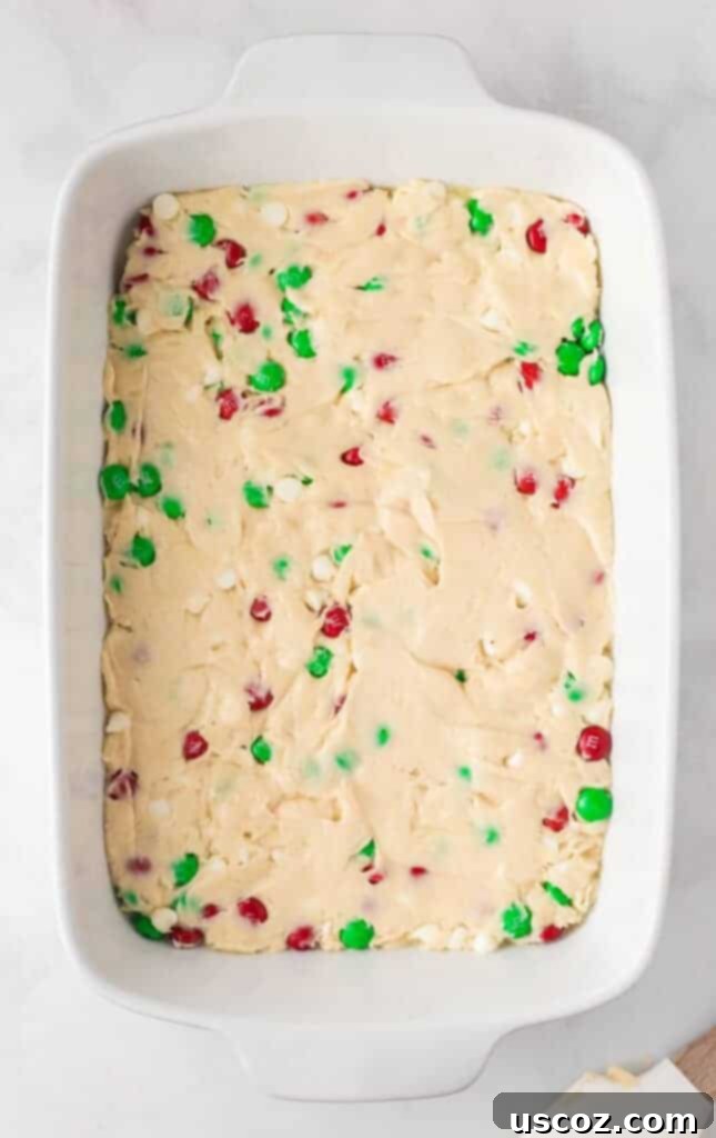 Merry Cookie Bar Magic 11 cookie bar batter spread evenly in a white 9 by 13 baking dish