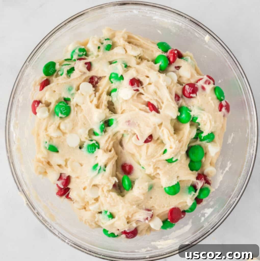 Merry Cookie Bar Magic 10 christmas cookie bar batter in a mixing bowl with M&M's and white chocolate chips mixed in