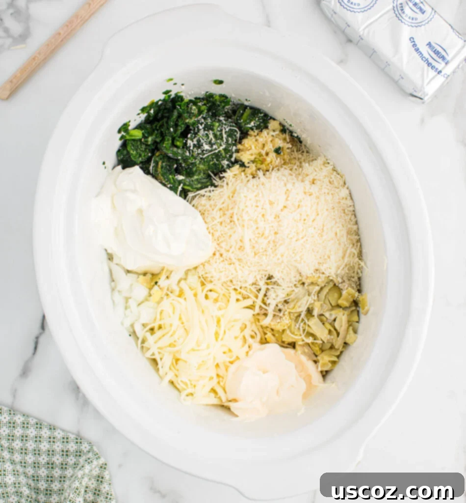 Creamy Slow Cooker Spinach Artichoke Dip 5 adding the ingredients to the crock pot