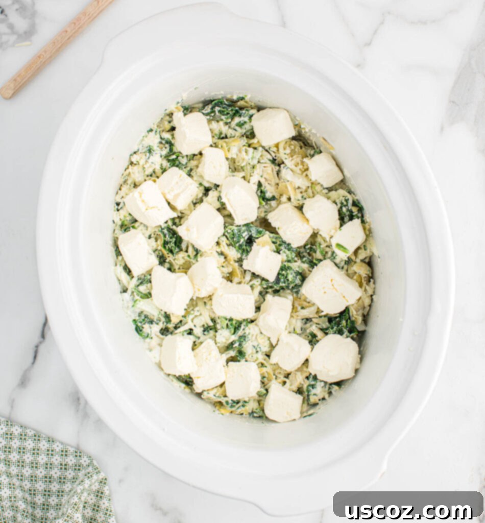 Creamy Slow Cooker Spinach Artichoke Dip 7 cream cheese chunks added to the top of the dip