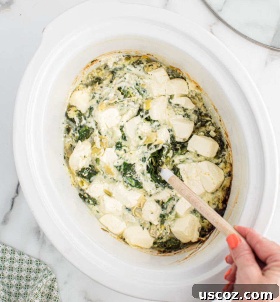 Creamy Slow Cooker Spinach Artichoke Dip 9 stirring the cream cheese into the dip
