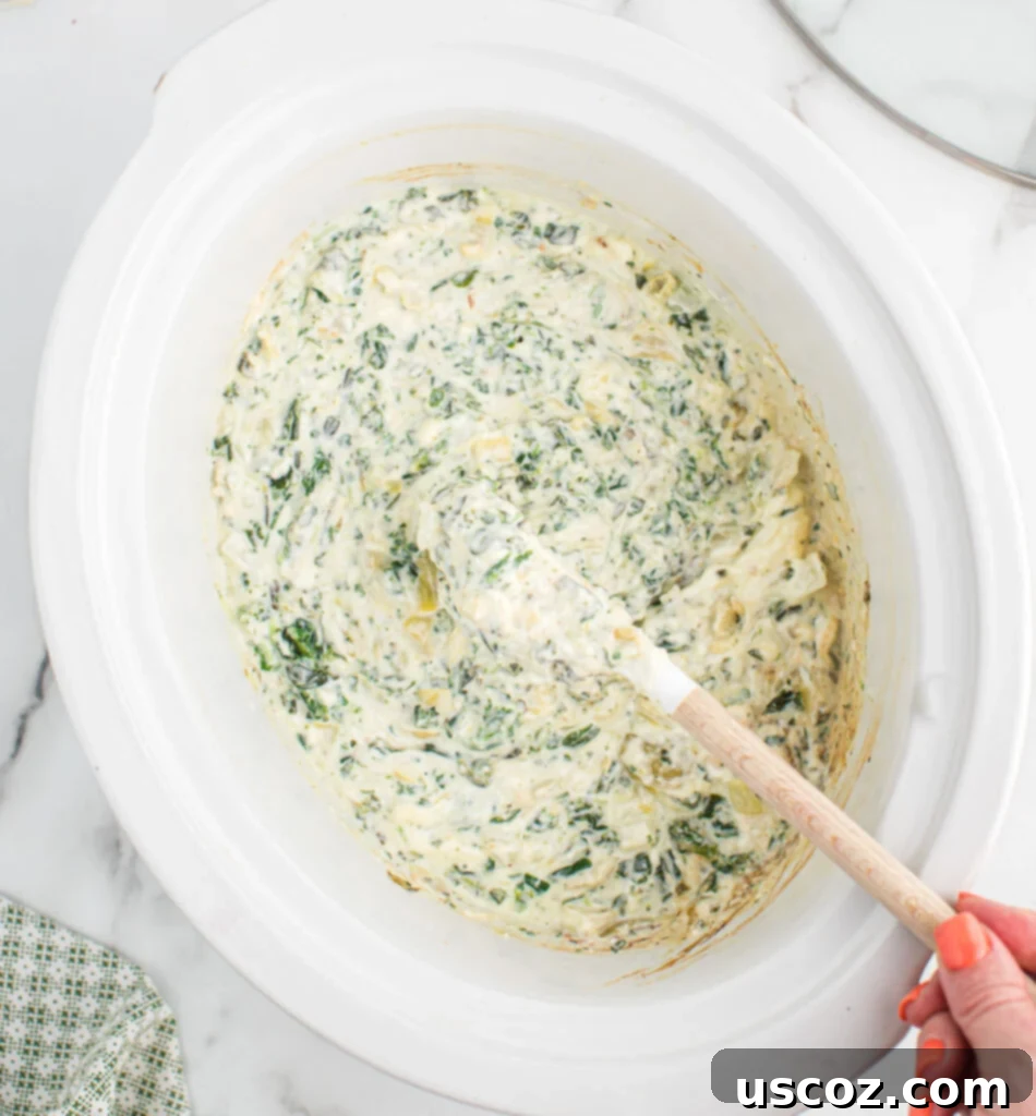 Creamy Slow Cooker Spinach Artichoke Dip 10 creamy slow cooker spinach artichoke dip being stirred