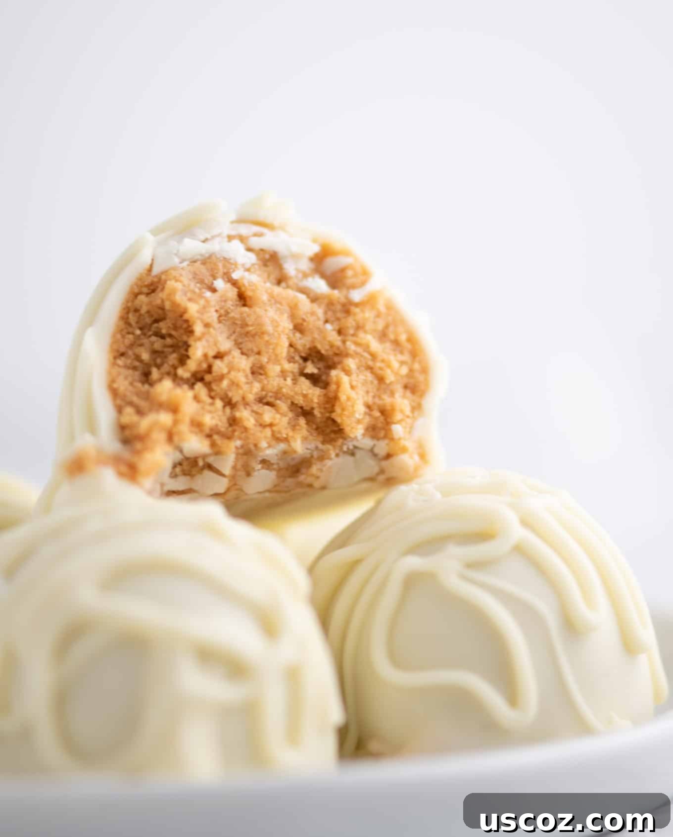 Decadent White Chocolate Peanut Butter Bliss Balls 6 white chocolate truffles with a bite taken out to show the peanut butter filling