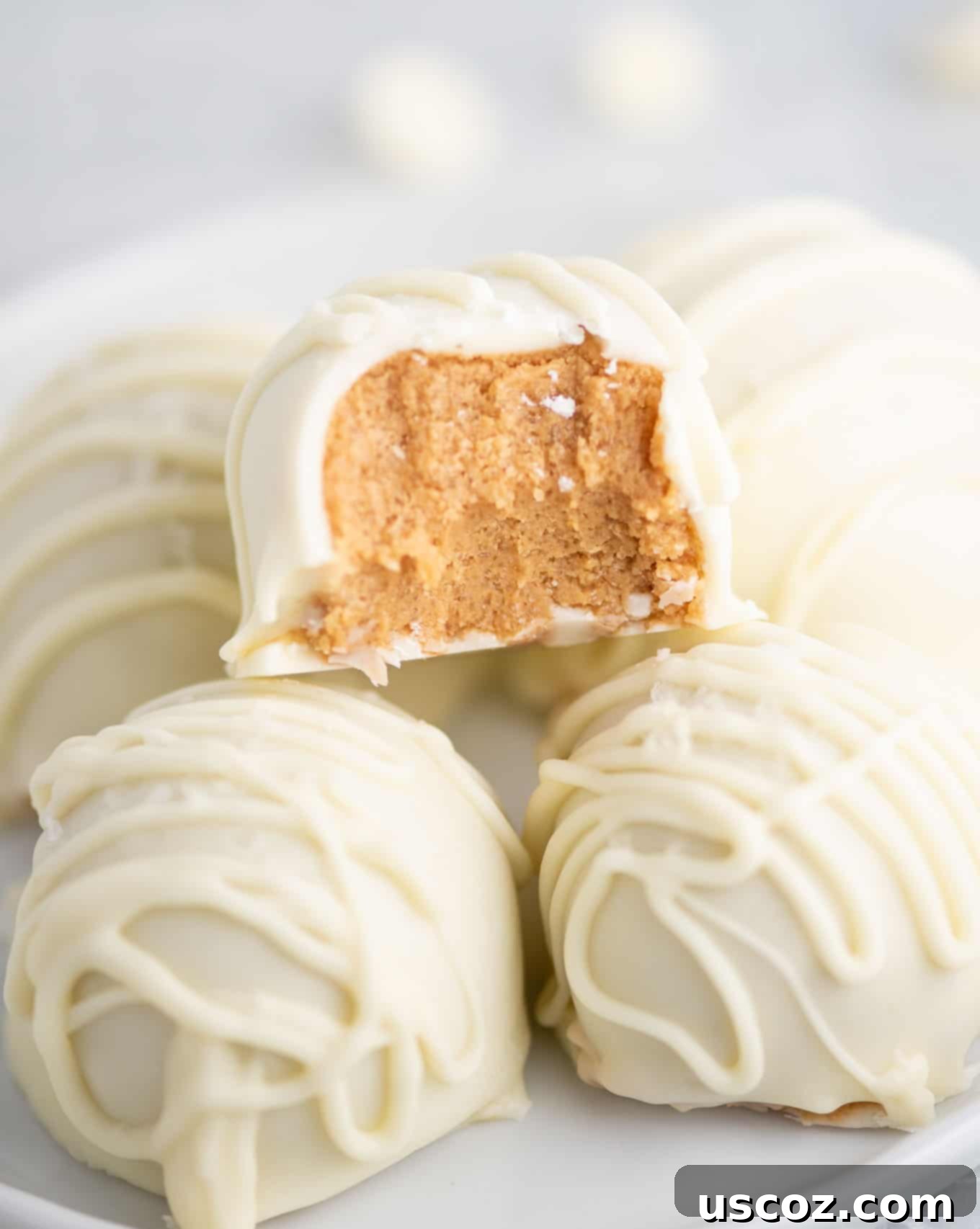 Decadent White Chocolate Peanut Butter Bliss Balls 10 peanut butter balls stacked with one taken a bite out of