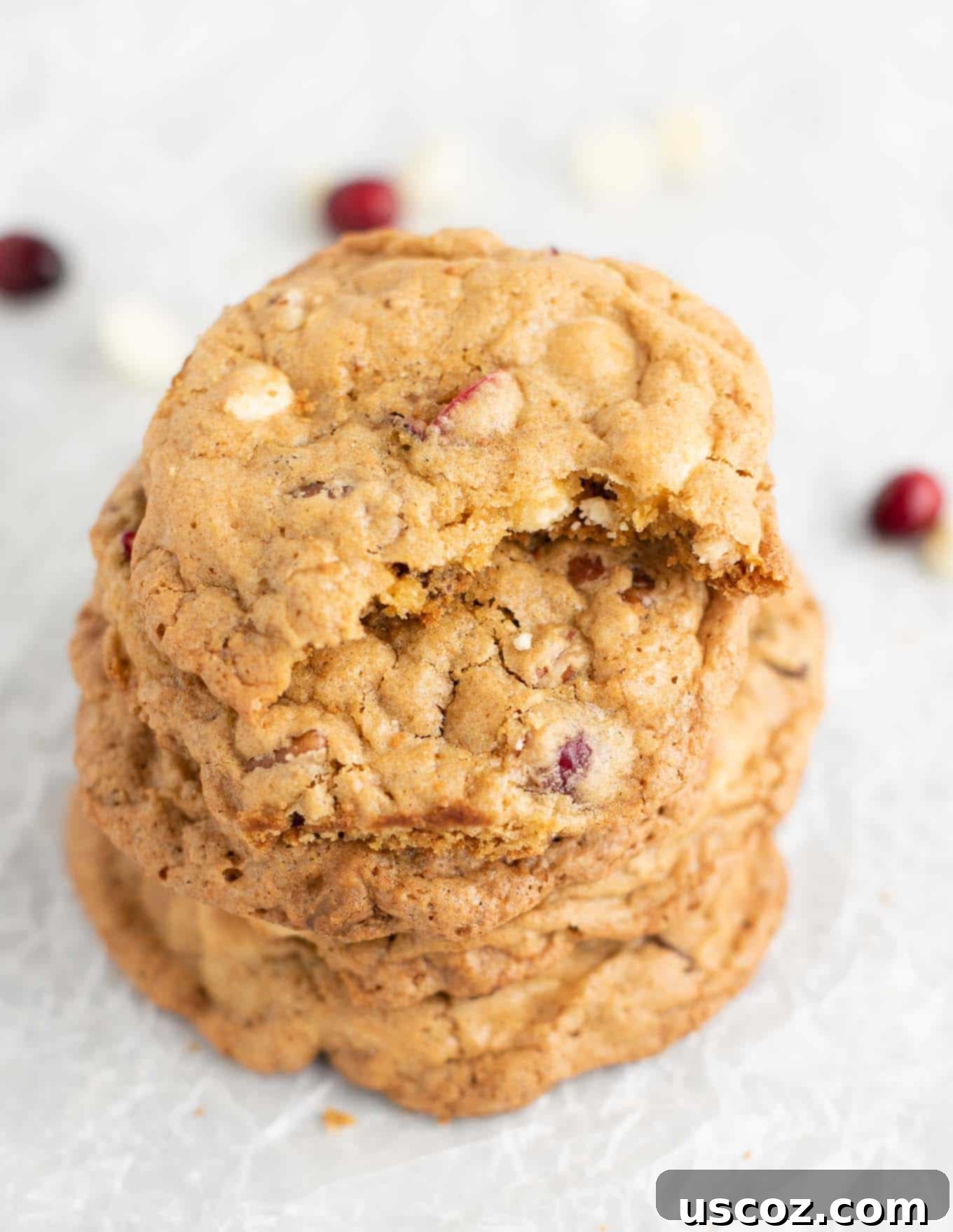 Cranberry Pecan White Chocolate Indulgence 3 Stack of freshly baked white chocolate cranberry pecan cookies, with one cookie showing a delicious bite taken out