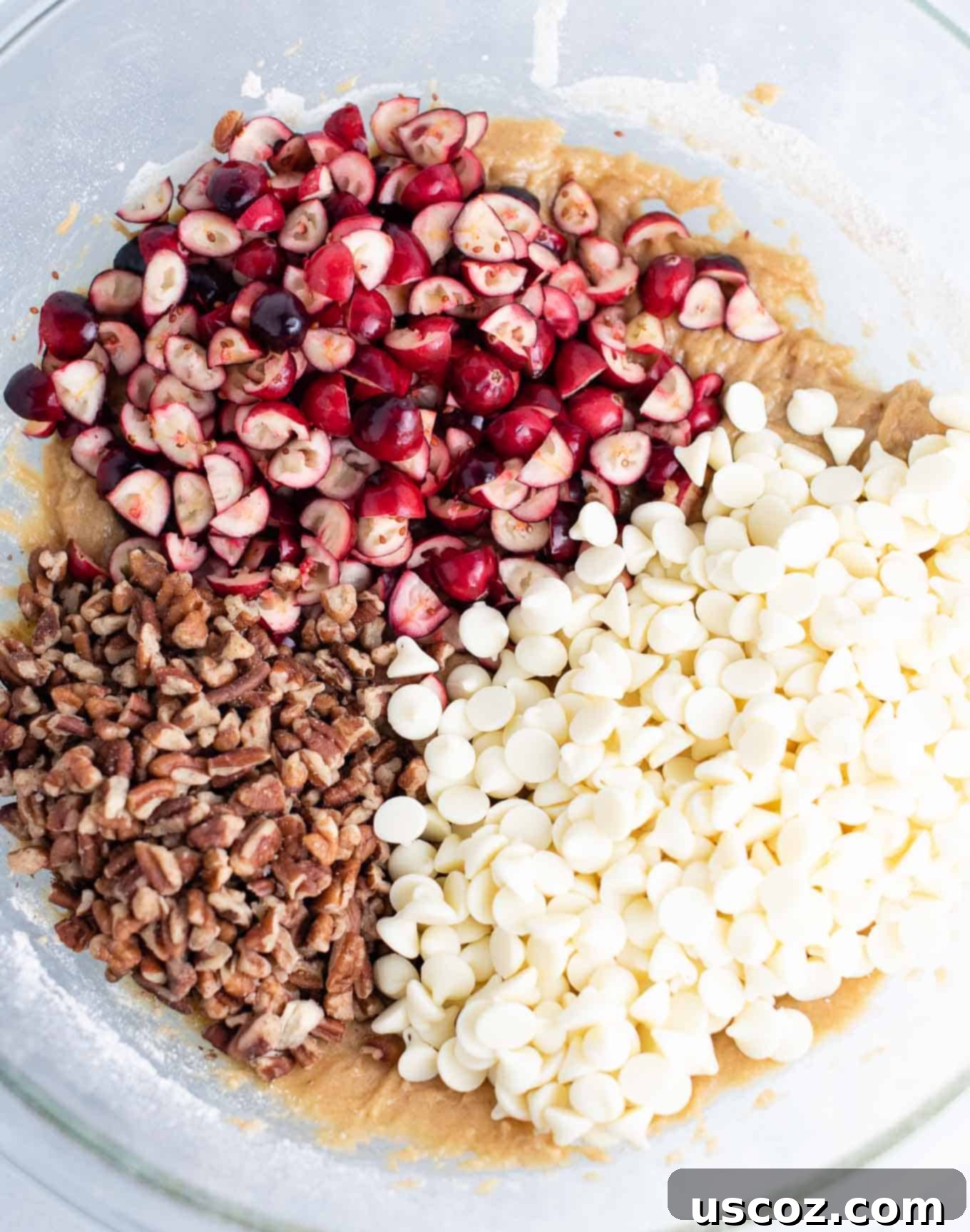 Cranberry Pecan White Chocolate Indulgence 4 Mixing bowl with cookie batter topped with vibrant chopped cranberries, crunchy chopped pecans, and sweet white chocolate baking chips