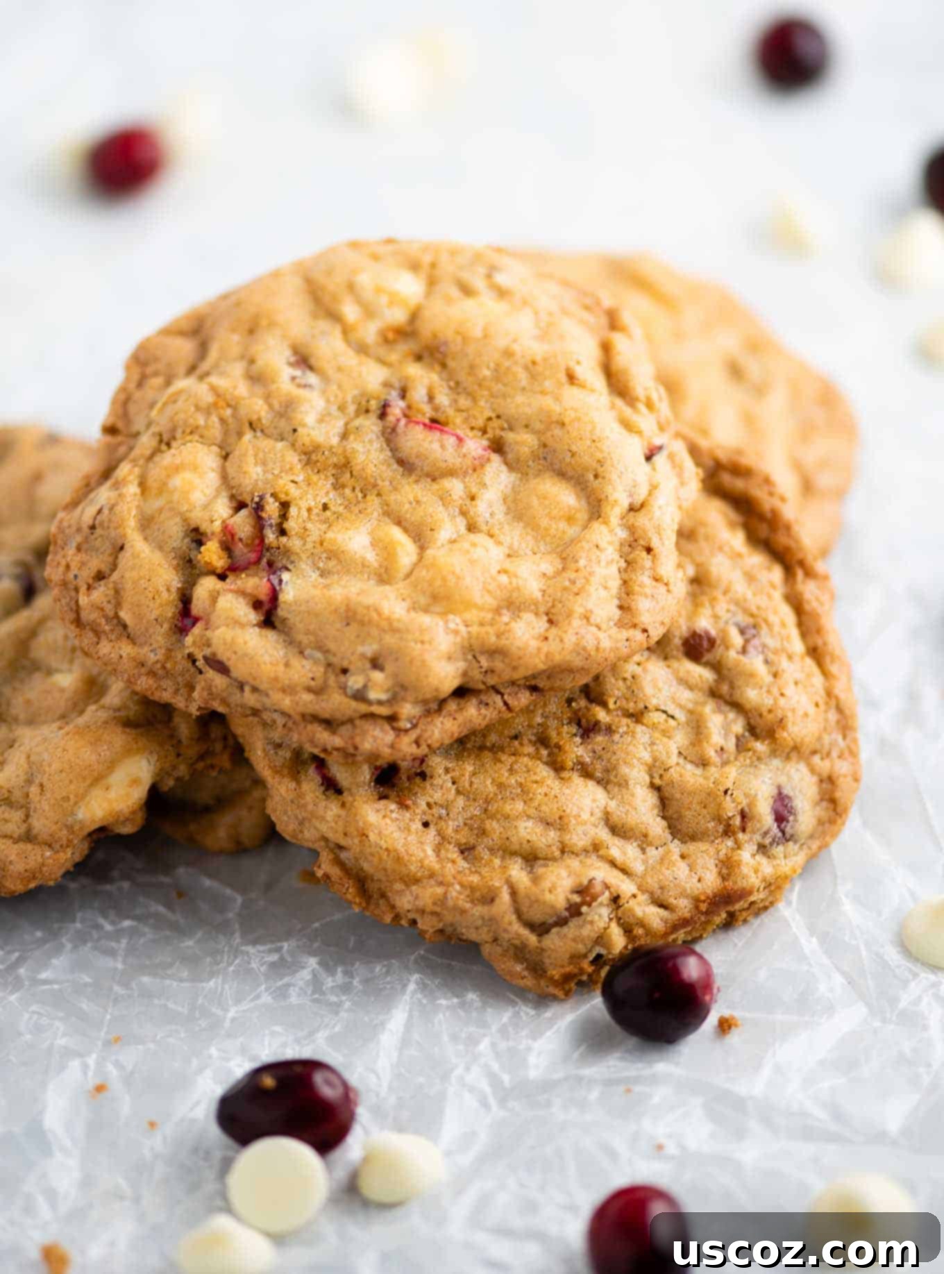 Cranberry Pecan White Chocolate Indulgence 9 White chocolate cranberry pecan cookies resting on crumbled wax paper, with scattered fresh cranberries and white chocolate chips in the background