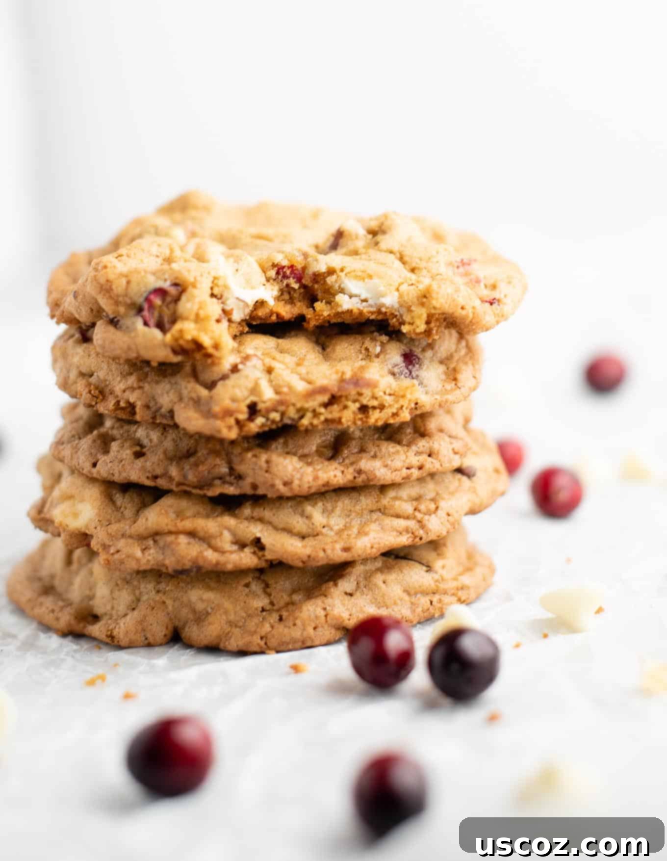 Cranberry Pecan White Chocolate Indulgence 10 Stacked white chocolate cranberry pecan cookies with one showing a bite, on a rustic wooden surface
