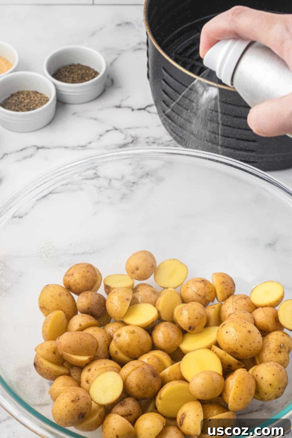 Crispy Golden Air Fryer Baby Potatoes 6 spraying a bowl of potatoes with olive oil spray