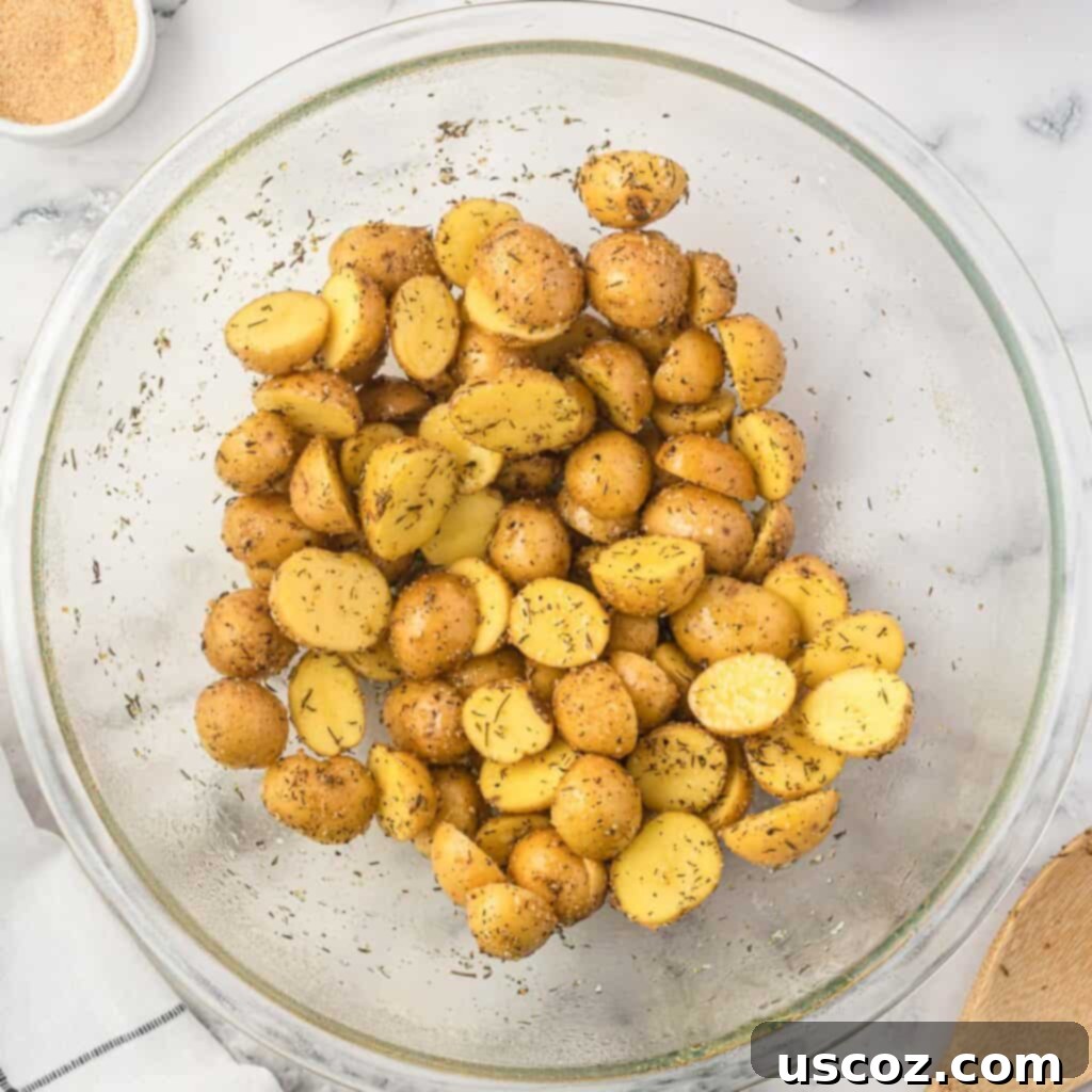 Crispy Golden Air Fryer Baby Potatoes 8 baby potatoes in a bowl mixed together with olive oil and spices