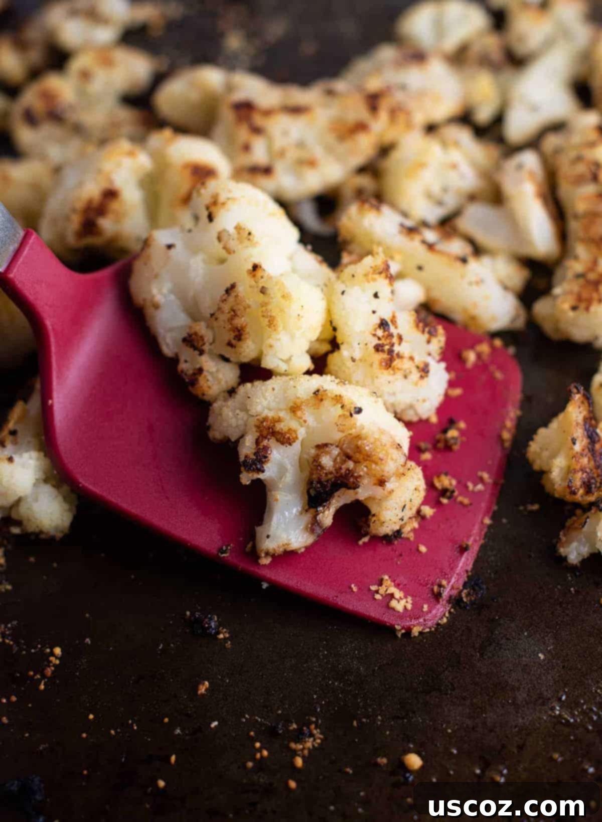 Crispy Roasted Frozen Cauliflower 2 Crispy oven roasted frozen cauliflower on a baking sheet being served with a red spatula