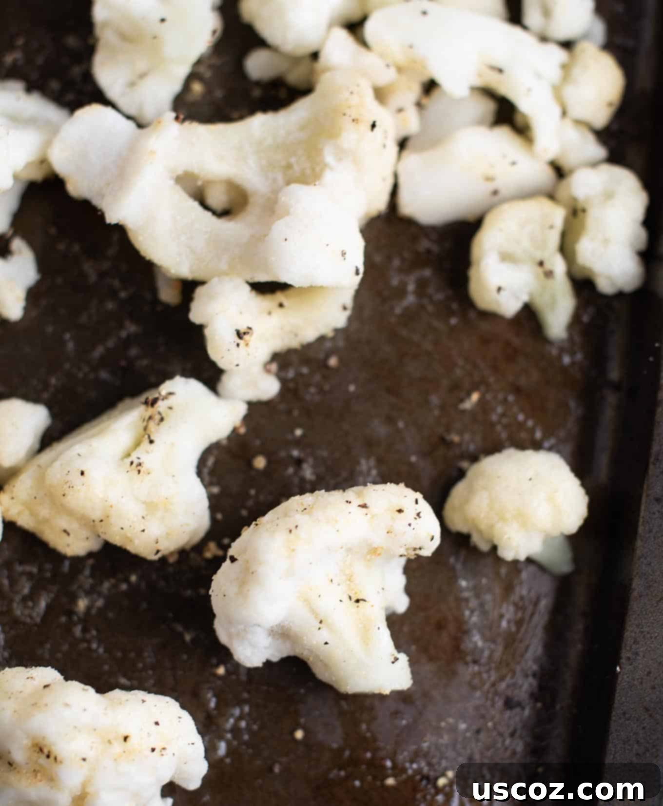 Crispy Roasted Frozen Cauliflower 4 Frozen cauliflower florets arranged evenly on a baking sheet with sprinkled spices before roasting