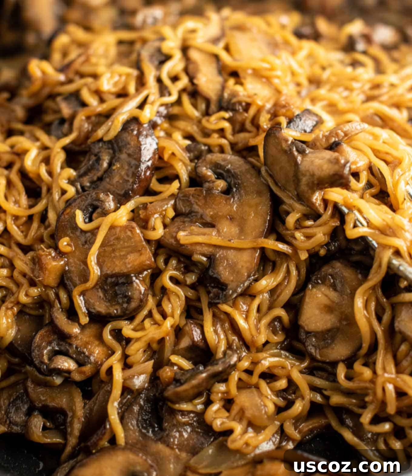 Umami Mushroom Ramen 8 A close-up shot of stir-fried noodles and mushrooms in a pan, glistening with sauce.