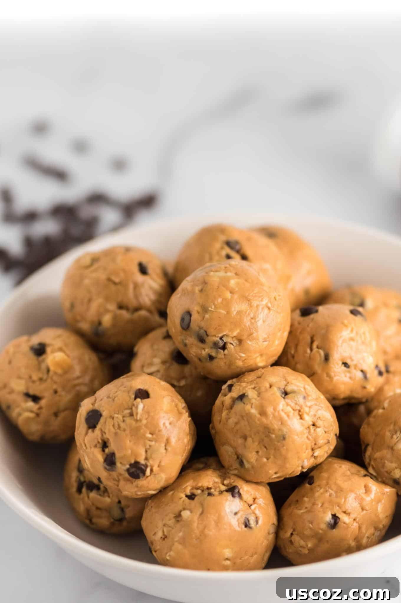 Wholesome Energy Bites 3 A bowl filled with freshly made energy balls, with chocolate chips scattered in the background, ready for snacking