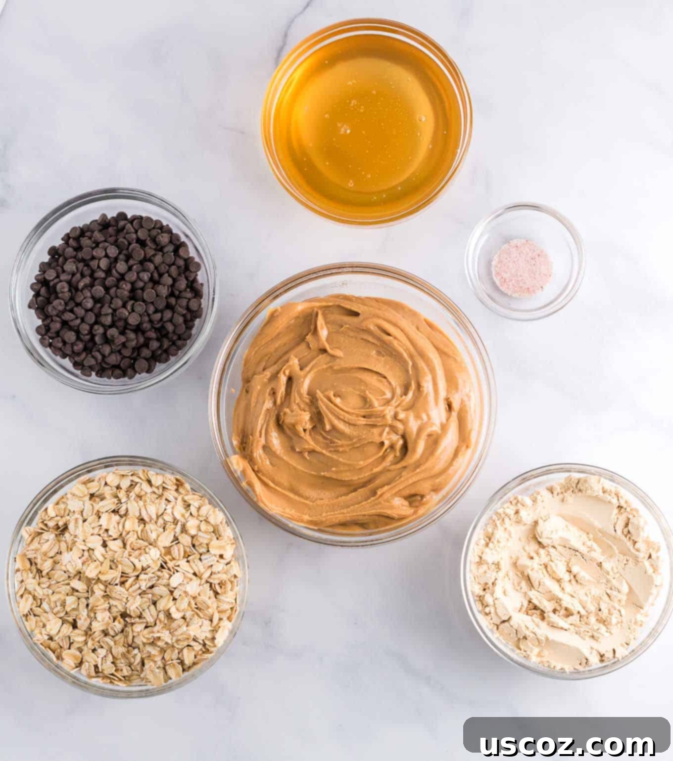 Wholesome Energy Bites 4 An overhead view of the six simple ingredients laid out: peanut butter, protein powder, salt, rolled oats, honey, and mini chocolate chips
