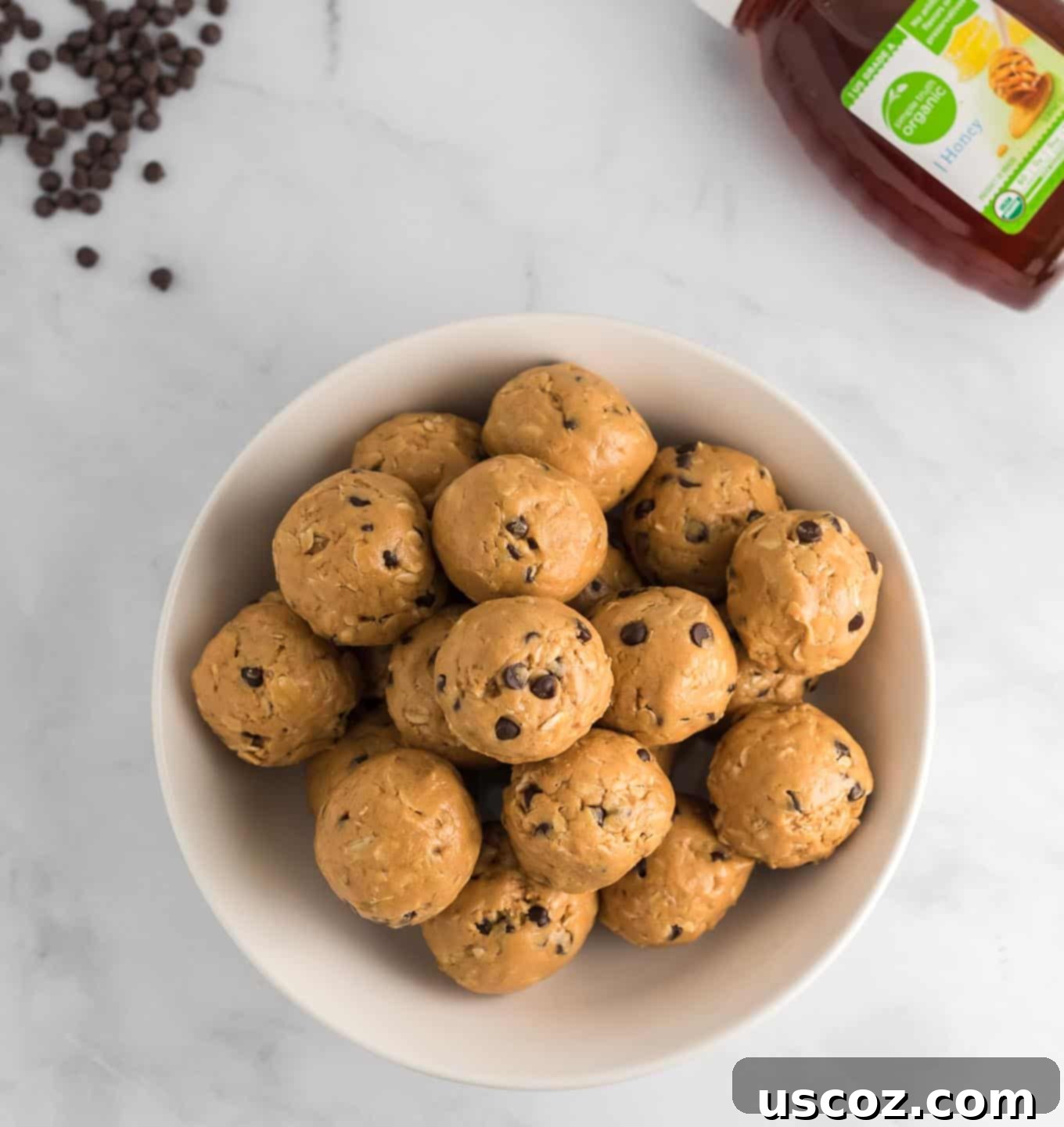 Wholesome Energy Bites 8 A perfectly formed energy ball, highlighting its texture with hints of honey and chocolate chips in the background