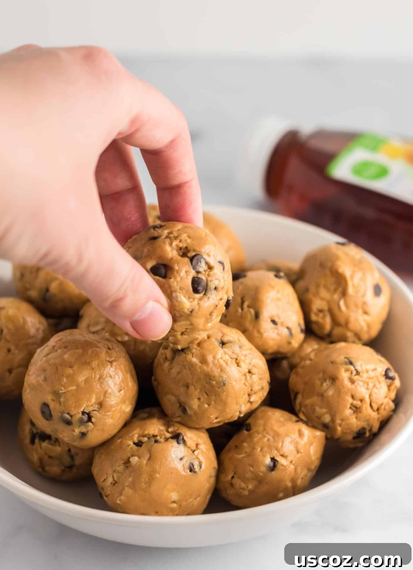 Wholesome Energy Bites 9 Fingers reaching for an energy ball from a beautifully stacked bowl, ready for a healthy snack