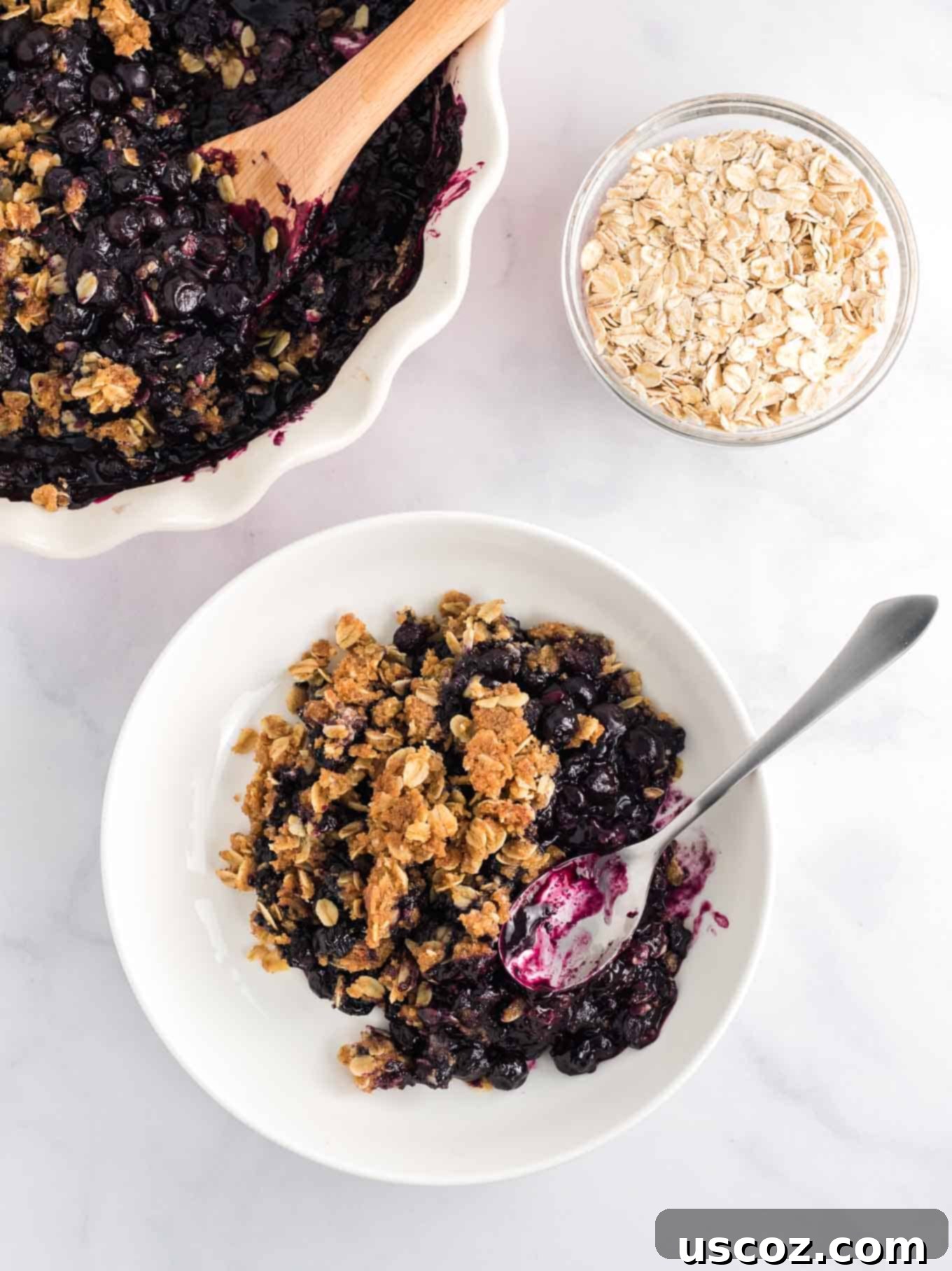 Warm Blueberry Crisp Delight 3 Overhead view of blueberry crisp in a white bowl, showing the bubbly fruit filling and textured oat topping.