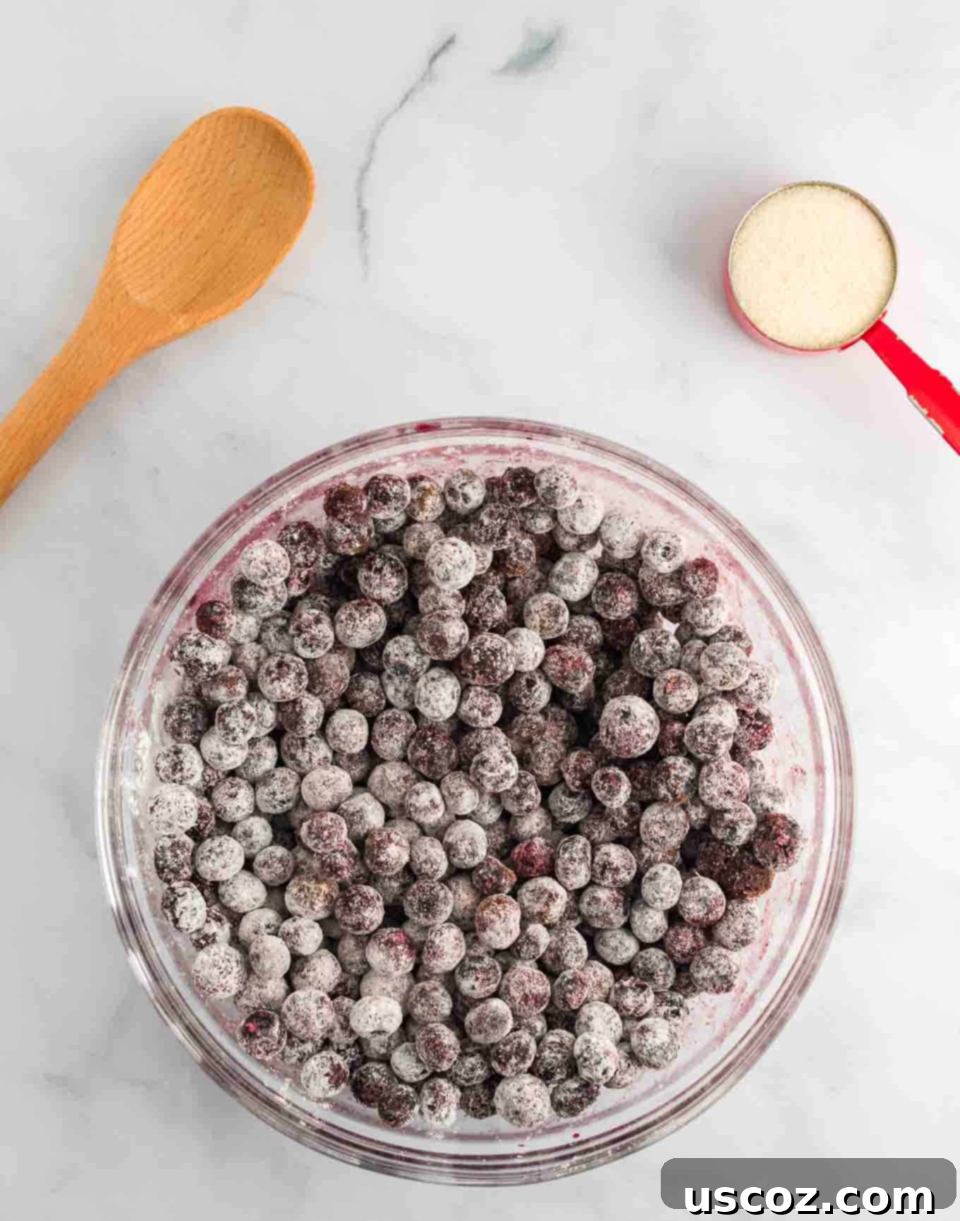 Warm Blueberry Crisp Delight 5 Frozen blueberries in a glass bowl, recently mixed with cornstarch, sugar, and cinnamon, showing some icy spots.