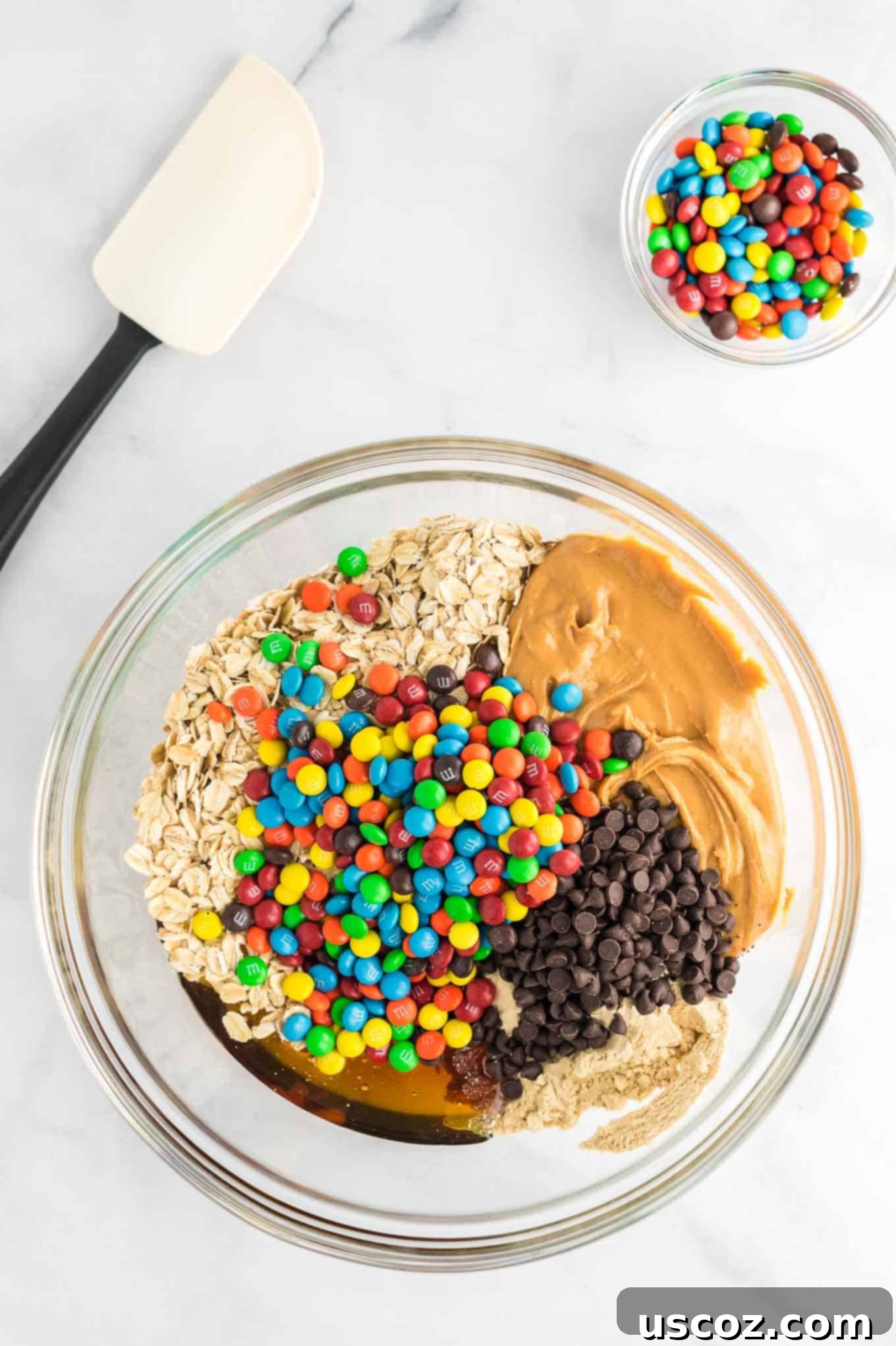 Monster Cookie Energy Bites 5 All the ingredients for Monster Cookie Energy Balls are combined in a large clear mixing bowl, ready to be mixed into a delicious dough.