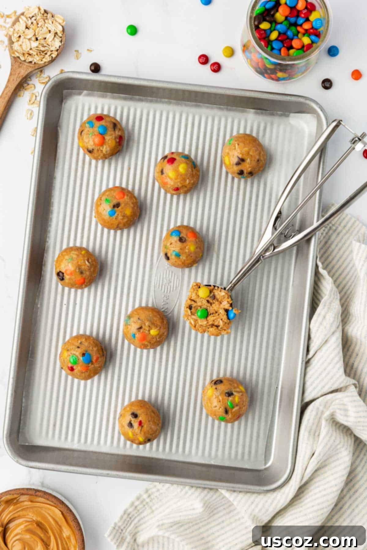 Monster Cookie Energy Bites 8 A baking sheet lined with wax paper holding an array of unchilled monster cookie bites, each ready for refrigeration.