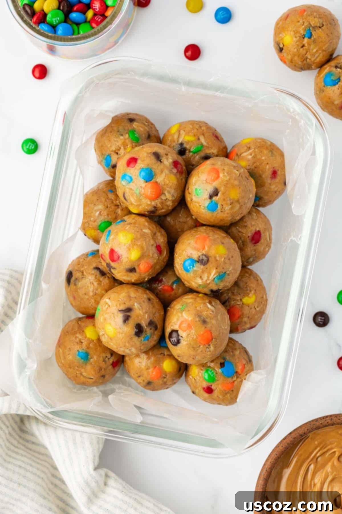 Monster Cookie Energy Bites 10 A clear plastic container filled with ready-to-eat monster cookie protein balls, showcasing their vibrant colors and perfect round shapes, ideal for storage.