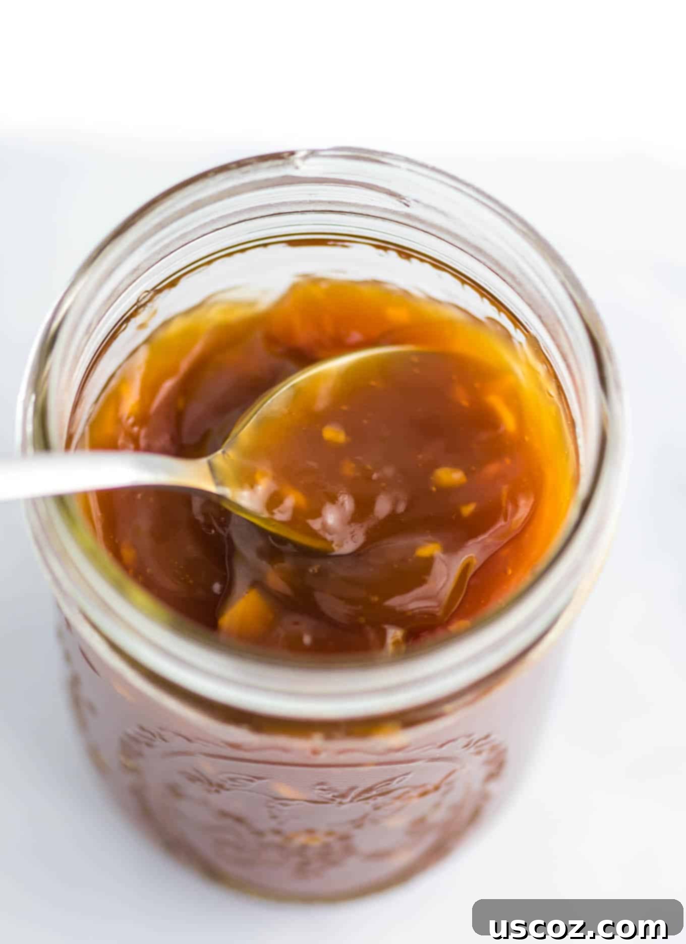 Zesty Orange Sauce 2 spoon inside a mason jar of orange sauce