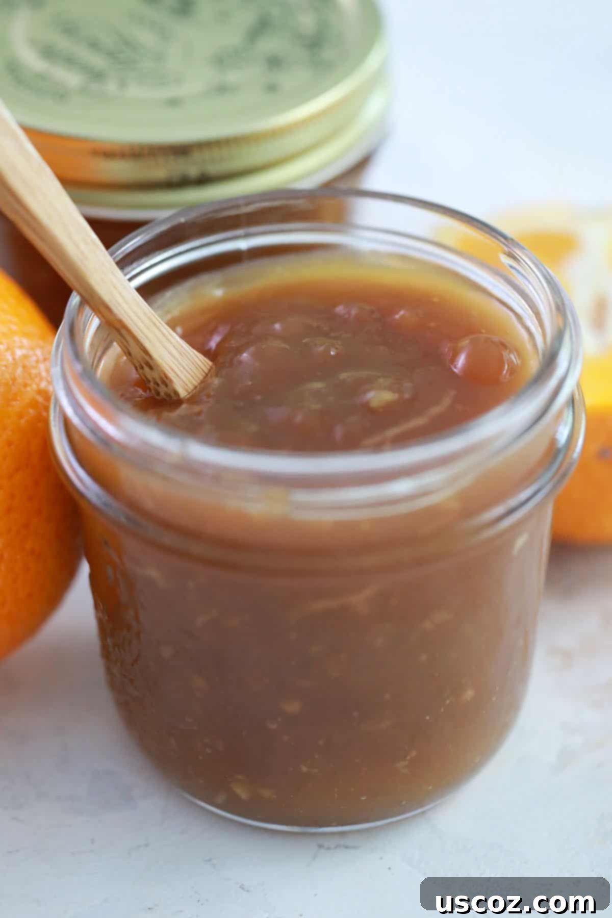 Zesty Orange Sauce 10 a jar full of orange sauce with a wooden spoon in it