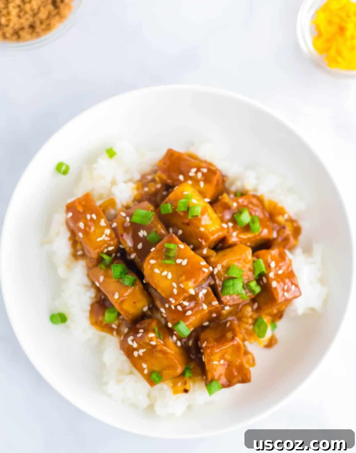 Zesty Orange Sauce 8 orange tofu in a white bowl with sesame seeds and green onions