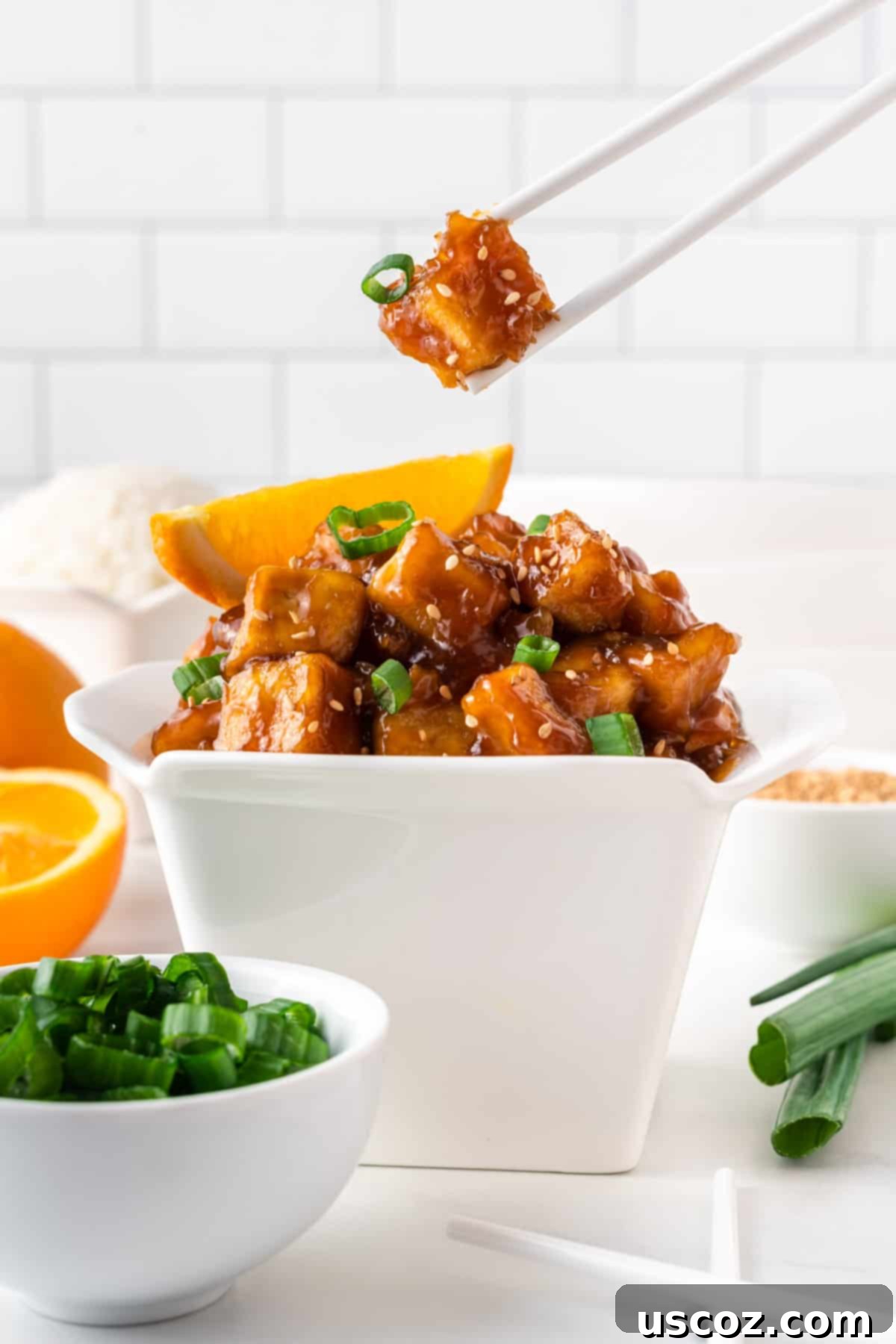 Zesty Orange Tofu 14 chopstick taking a piece of tofu from the takeout container