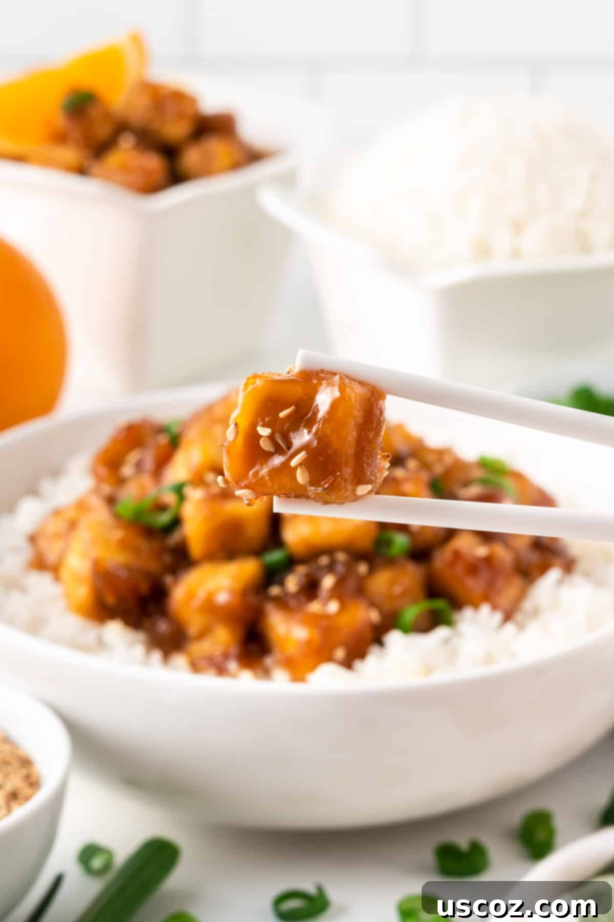 Zesty Orange Tofu 3 chopsticks holding a piece of orange tofu