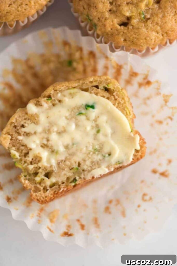 Sweet Zucchini Treats 2 Zucchini muffin cut in half with butter smeared on it, showing its moist interior.