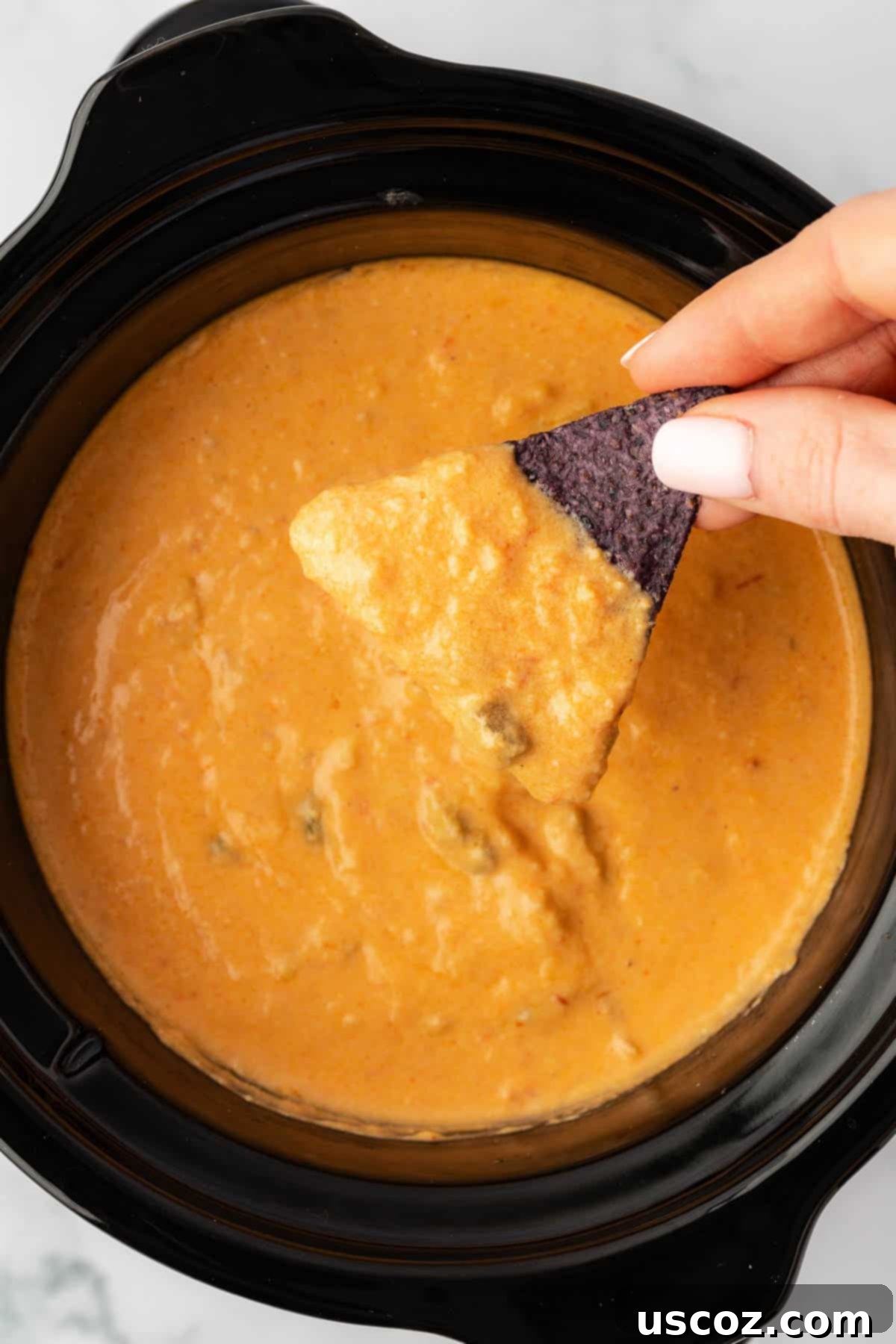 Easy Crock Pot Queso Dip 10 chip being dipped into queso dip