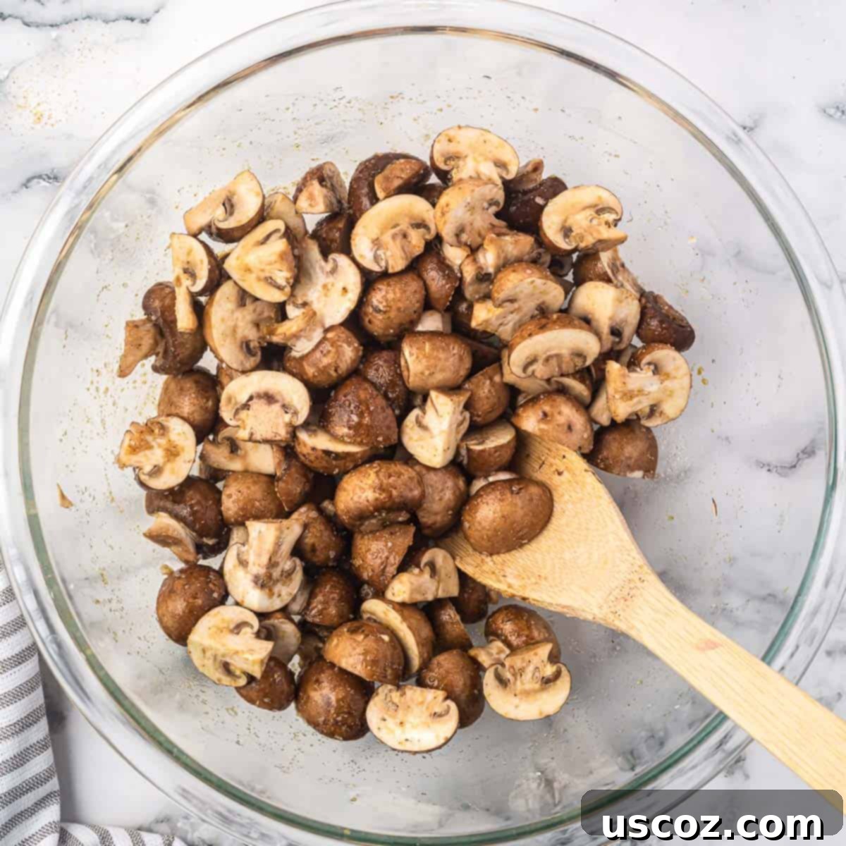 Crispy Air Fryer Mushrooms 6 cut mushrooms in a bowl mixed together with the oil and spices