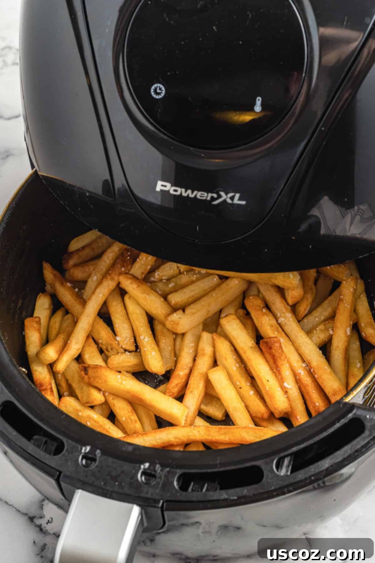 Perfectly Crispy Air Fryer Frozen Fries 4 A close-up of golden brown and super crispy french fries neatly arranged in the air fryer basket, freshly cooked and ready to be removed.