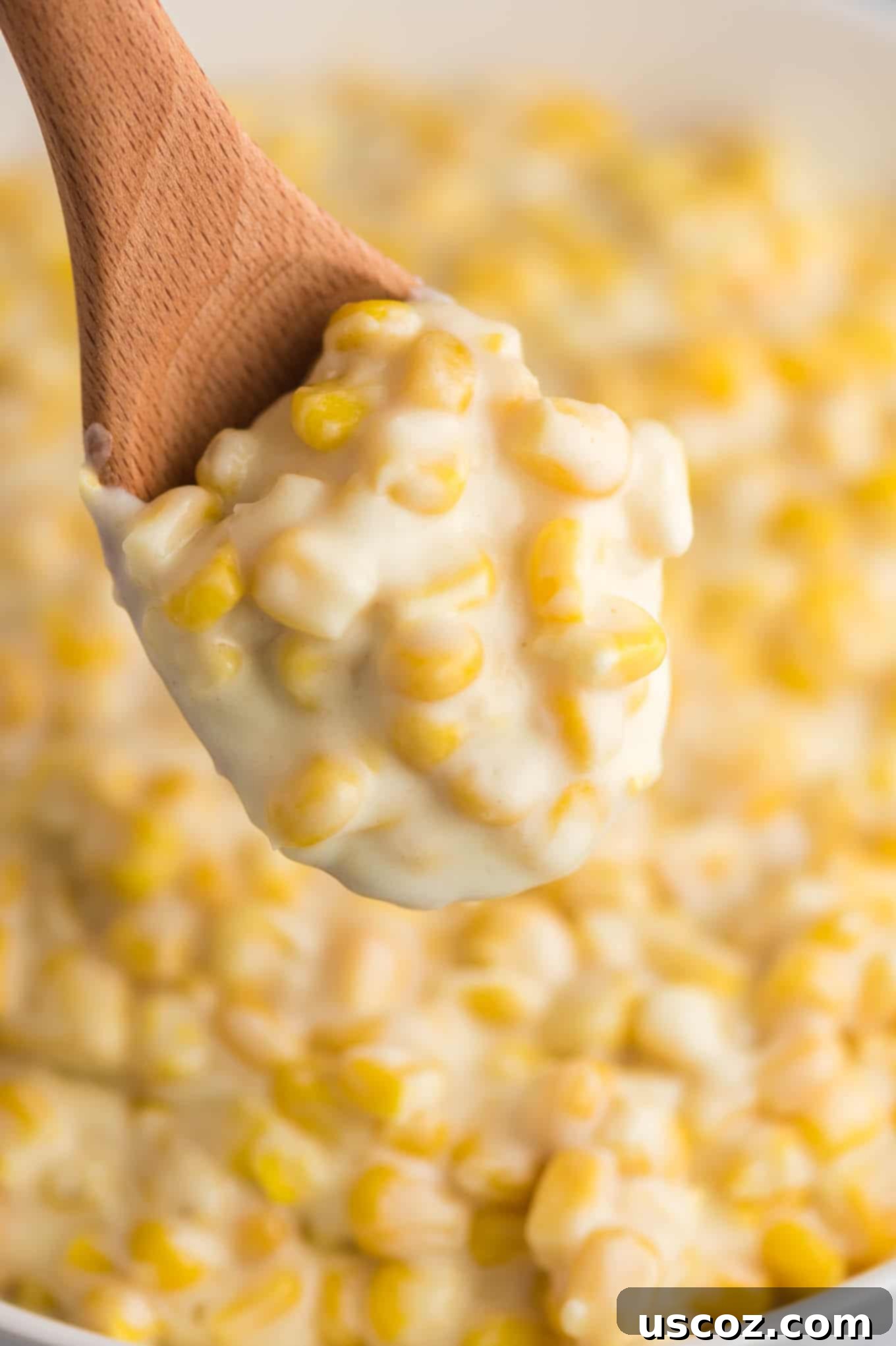Dreamy Creamed Corn 8 A wooden spoon scooping into a generous portion of richly textured, golden creamed corn, ready to be served and enjoyed as a delicious comfort food.