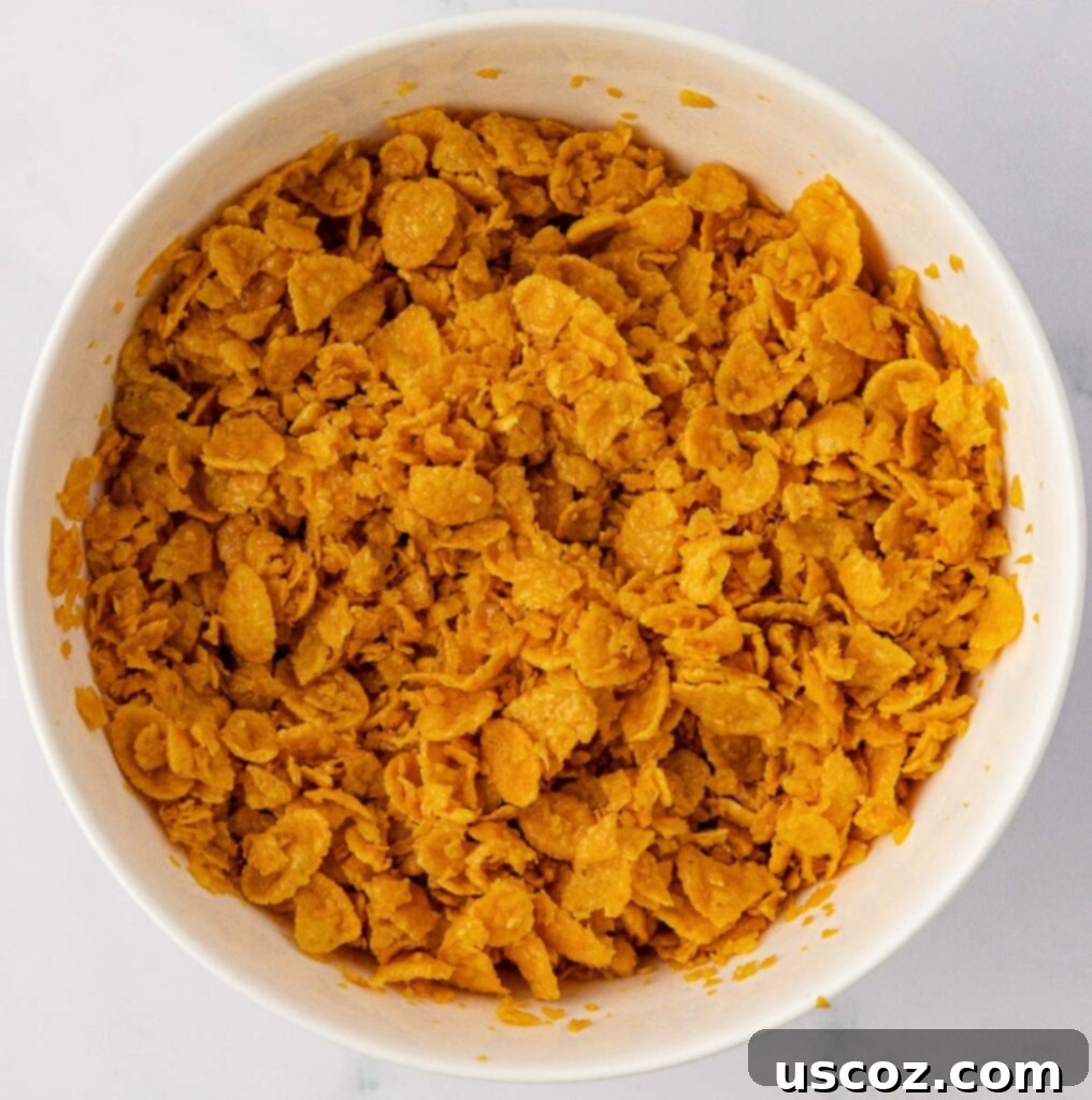 Crispy Cheesy Potato Casserole 13 Crushed corn flakes mixed with melted butter in a bowl, showing the prepared topping.