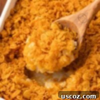 Crispy Cheesy Potato Casserole 19 A scoop of funeral potatoes being taken from the baking dish, showing the creamy texture and crispy topping.