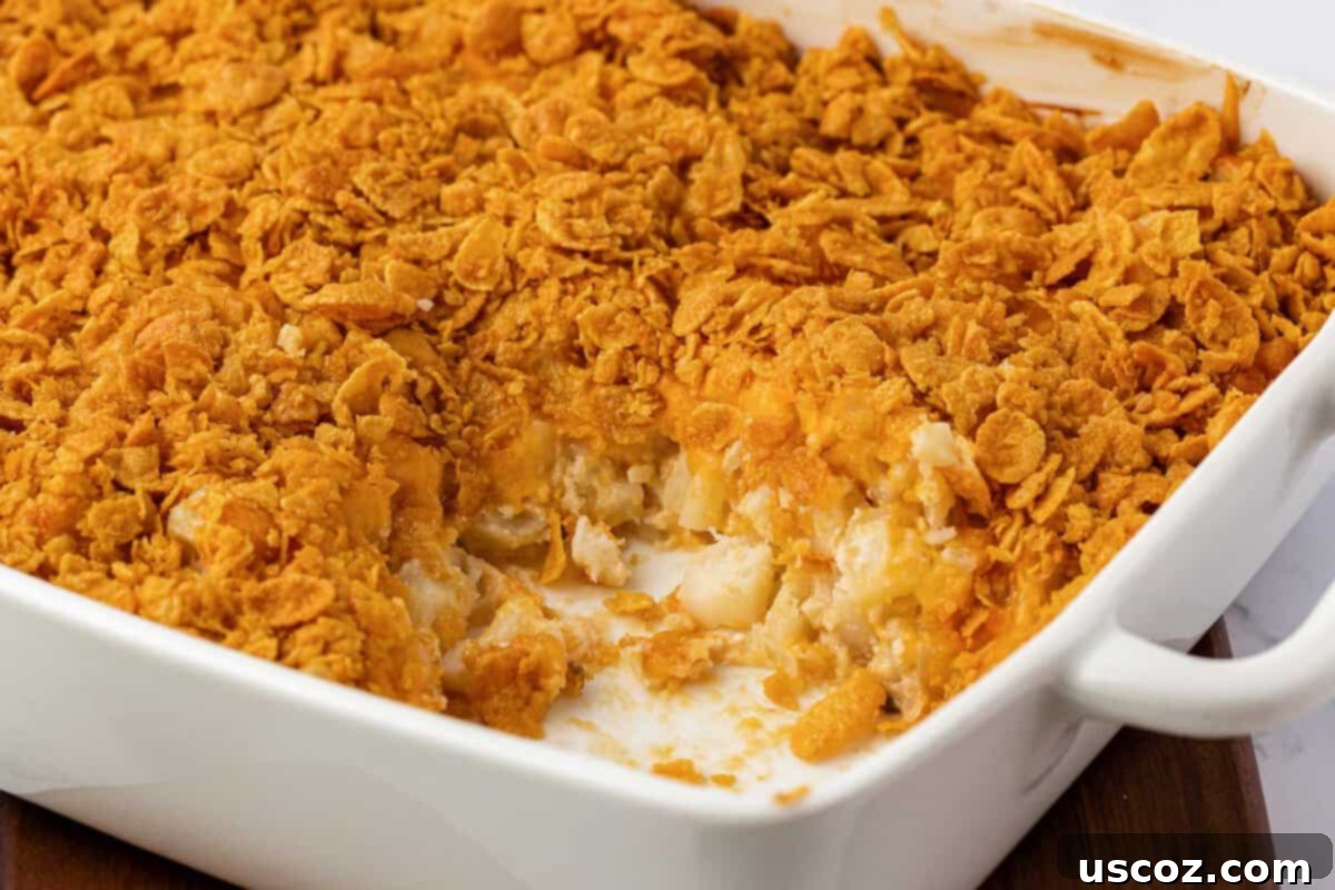 Crispy Cheesy Potato Casserole 3 A close-up of the finished cheesy potatoes with a golden, crunchy corn flake topping, served in a white baking dish, ready to be enjoyed.