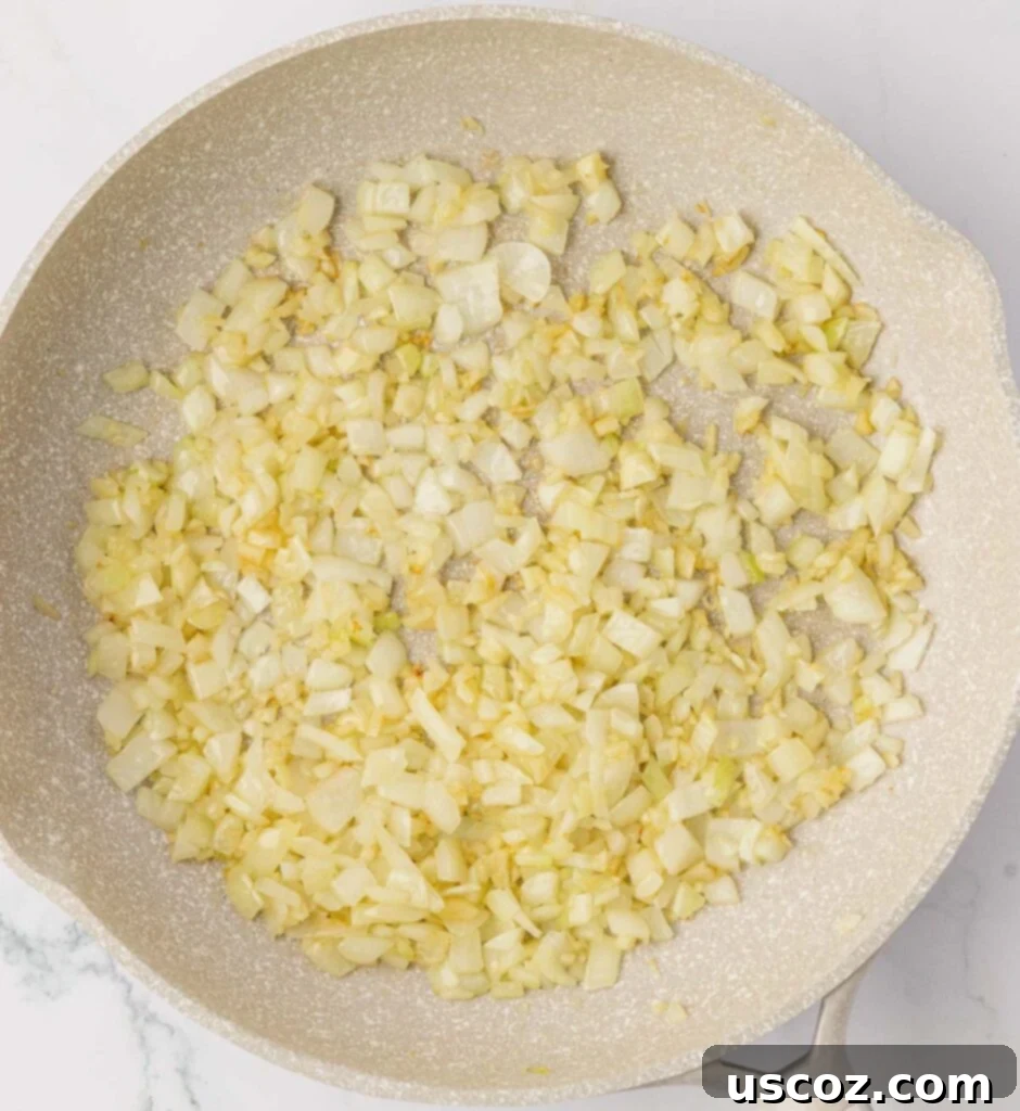 Crispy Cheesy Potato Casserole 5 Diced garlic, onion, and melting butter sizzling in a skillet on a stovetop, capturing the start of the cooking process.