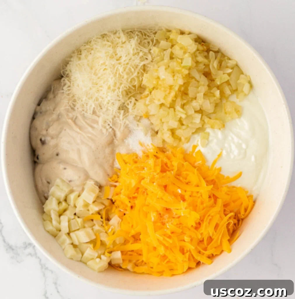 Crispy Cheesy Potato Casserole 7 Various funeral potato ingredients, including thawed hash browns, cream of mushroom soup, and cheeses, waiting to be mixed in a large bowl.