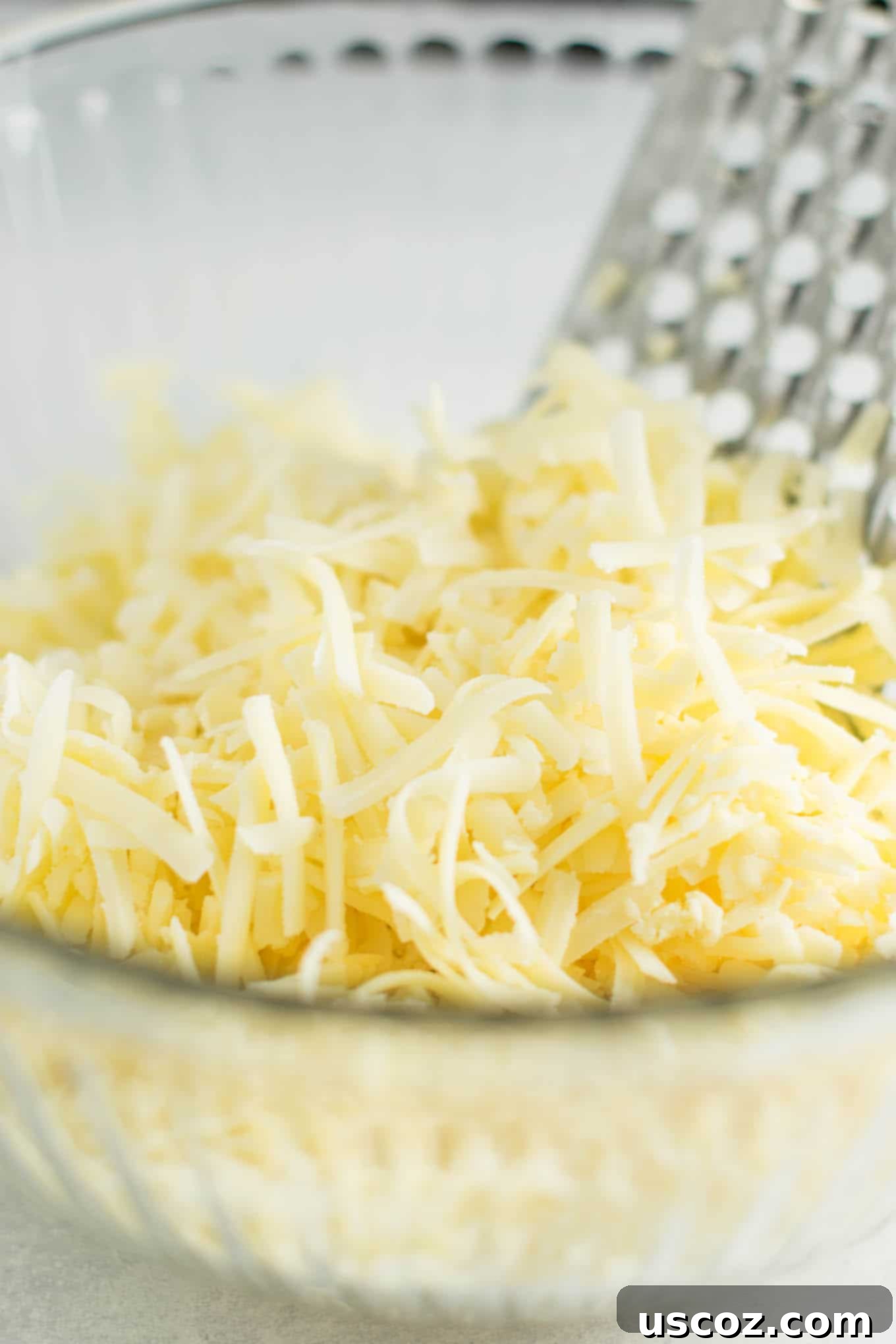 Robust Sharp Cheddar Mac and Cheese 4 hands grating a block of sharp cheddar cheese