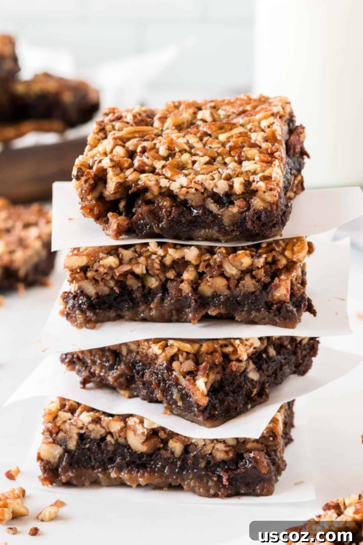 Ultimate Pecan Pie Brownies 16 pecan pie brownies stacked between pieces of parchment paper