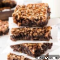 Ultimate Pecan Pie Brownies 17 pecan pie brownies stacked between pieces of parchment paper