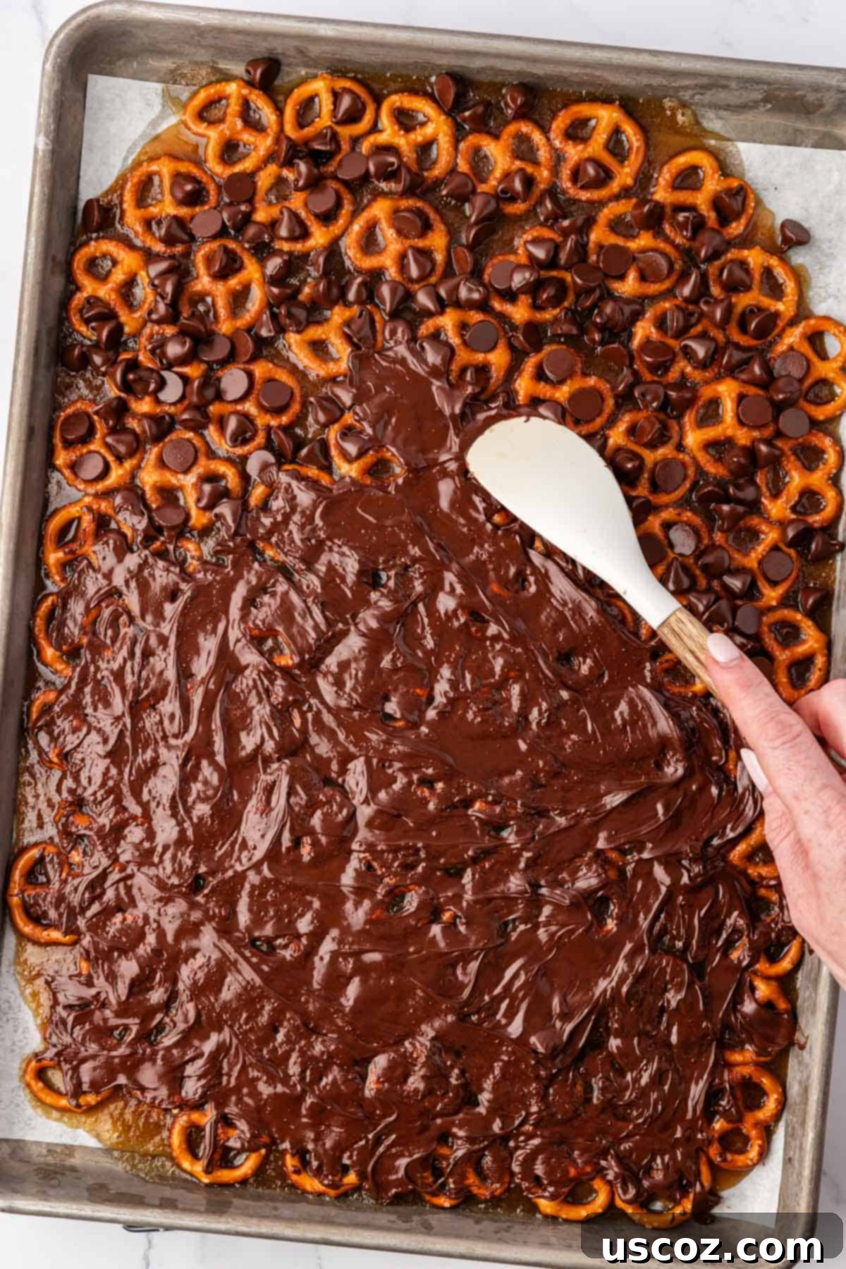 Holiday Pretzel Crunch 15 spreading the melted chocolate over the pretzels with a rubber spatula