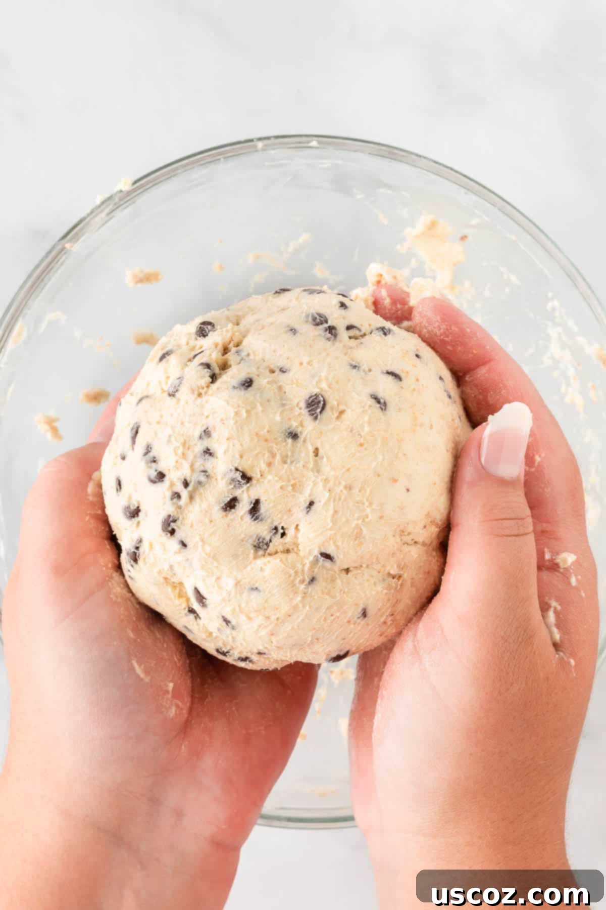 Chocolate Chip Cheese Ball Delight 11 Hands shaping the chilled chocolate chip dessert cheese ball batter into a round ball.