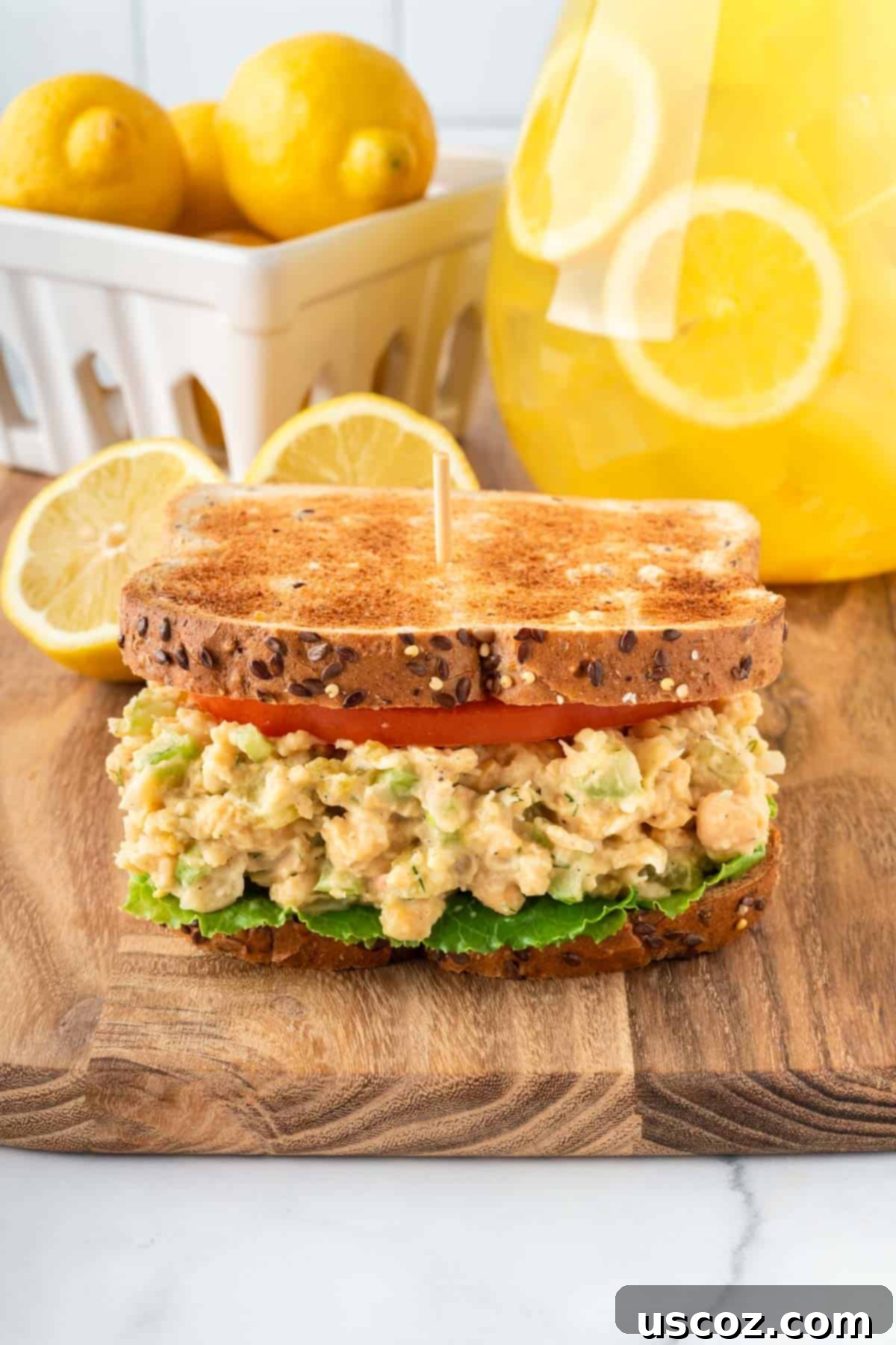 Creamy Dreamy Chickpea Salad Sandwich 12 Two halves of a delicious chickpea salad sandwich on whole wheat bread, garnished with fresh tomato and lettuce