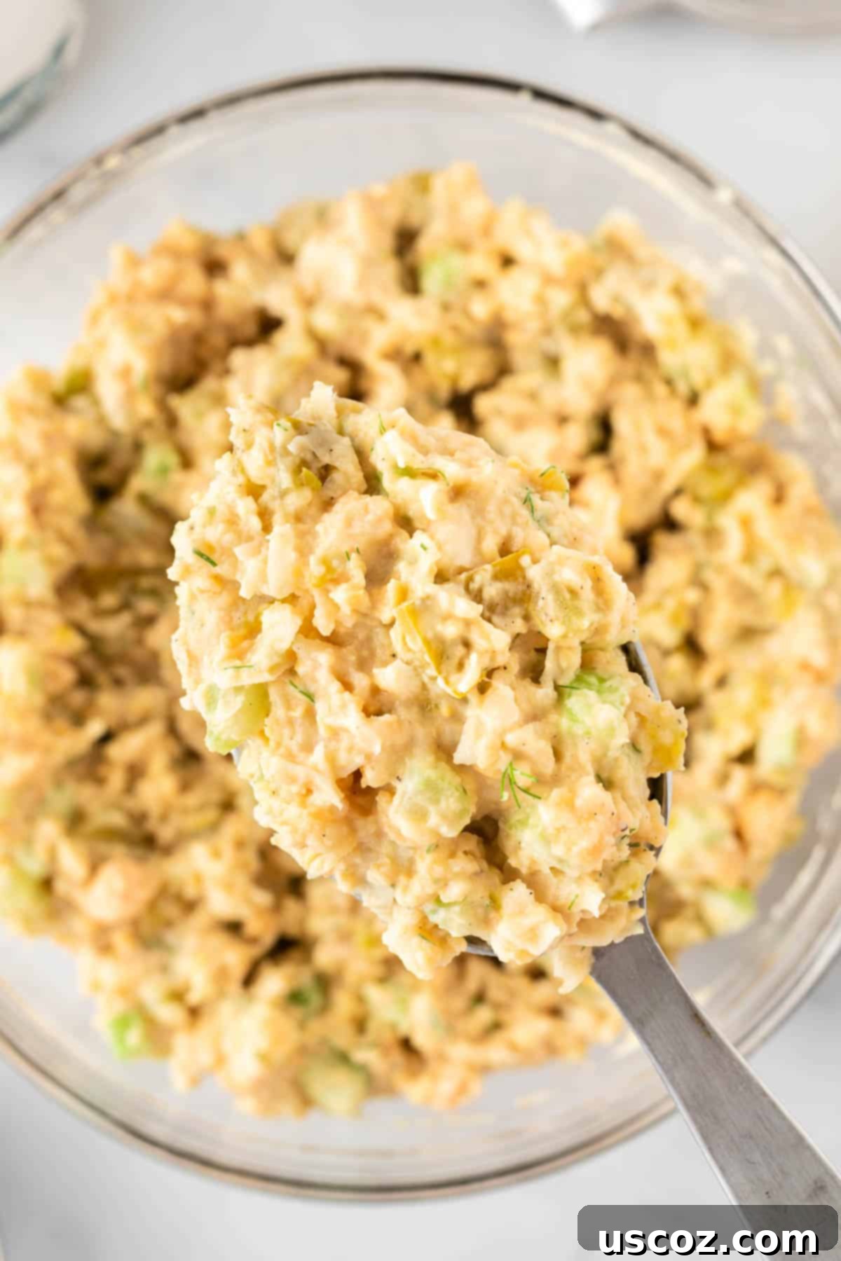 Creamy Dreamy Chickpea Salad Sandwich 9 Spoon scooping a generous portion of freshly made chickpea salad from a white bowl